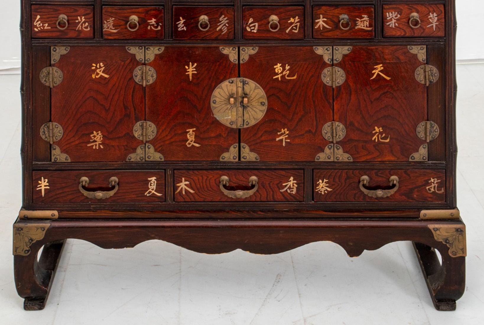 Korean apothecary or medicinal cabinet, 19th C or later, rectangular with winged top above thirty-six (36) labeled drawers and three cabinets on four shaped legs.

Dimensions: 34.5