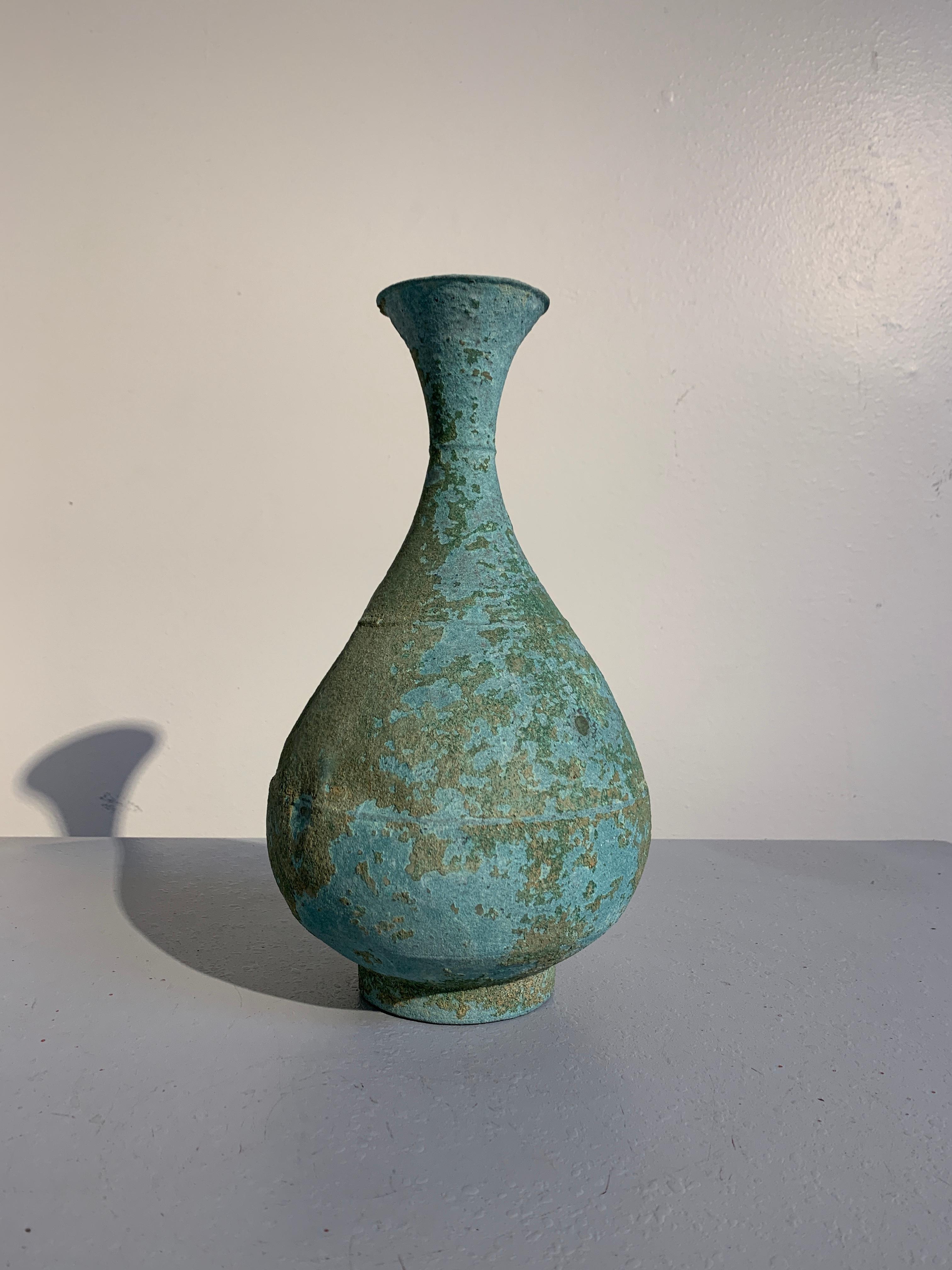 A stunningly patinated Korean ritual bronze bottle vase, Goryeo Dynasty, 12th-13th century, Korea.

The bronze bottle vase crafted from a thin bronze, with a pear shaped body, long tapering neck, and flaring mouth, all set upon a short ring foot.