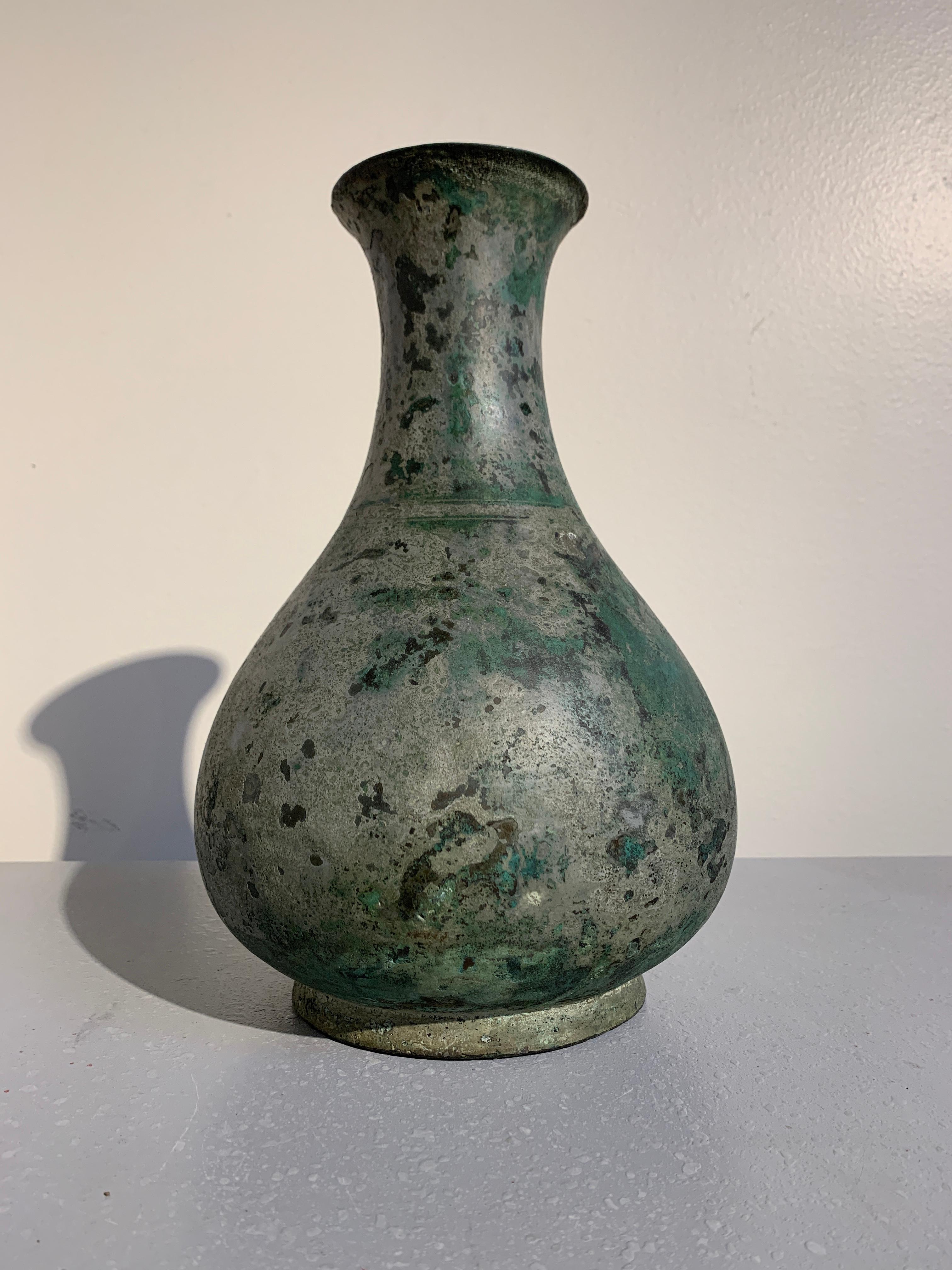 A stunningly patinated Korean Goreyo Dynasty ritual bronze bottle vase, 12th-13th century, Korea. 

The ritual bottle vase of pear shape. The squat body set upon a short foot with a wide neck rising to an everted mouth. 
The bronze vessel covered