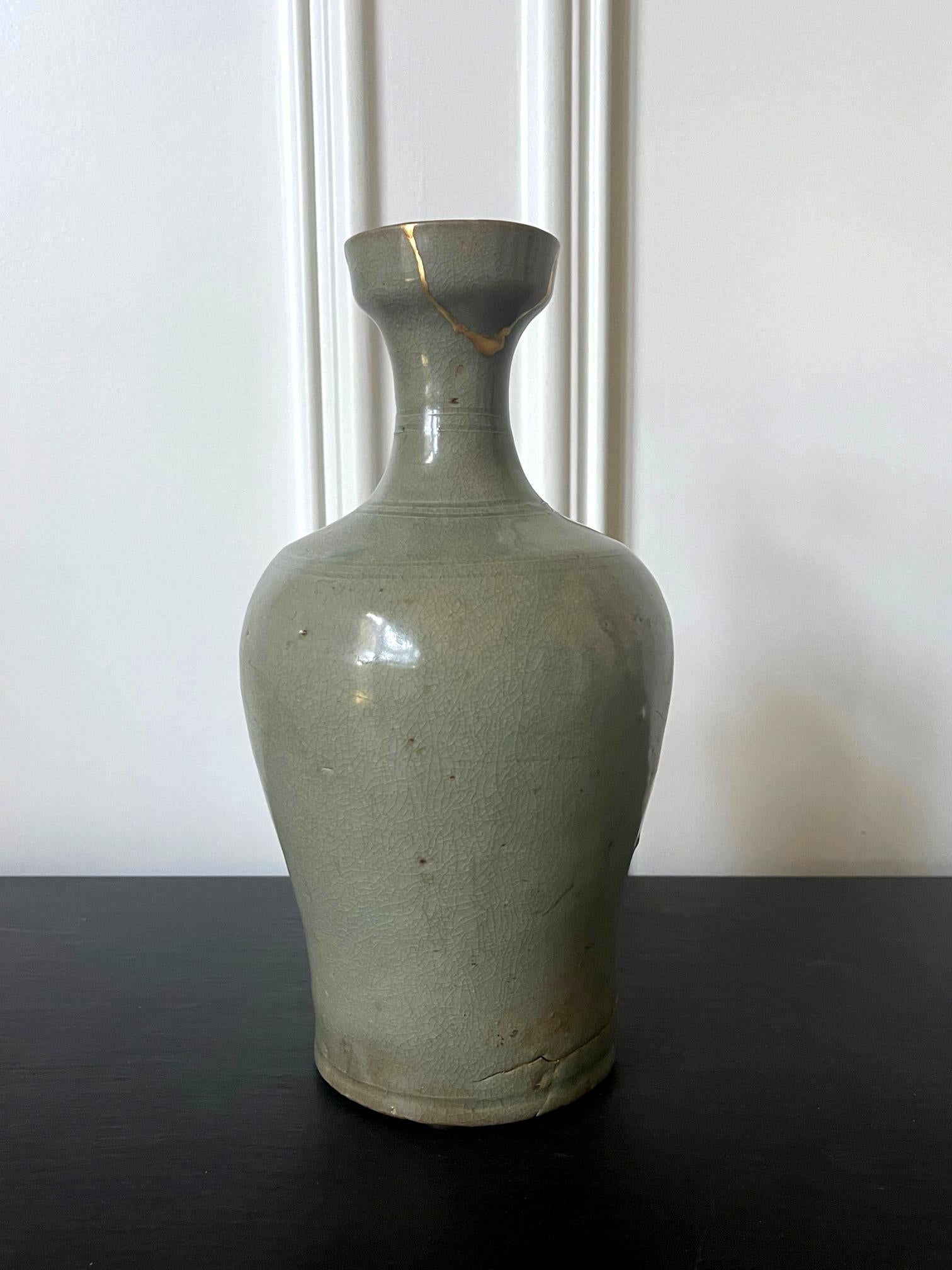 A ceramic wide-mouthed bottle vase covered in green celadon glaze from Goryeo dynasty circa 11-12th century. The bottle vase with such a form (mouth with wide rim, long and slender neck, tall body with swelled shoulders that taper down toward the