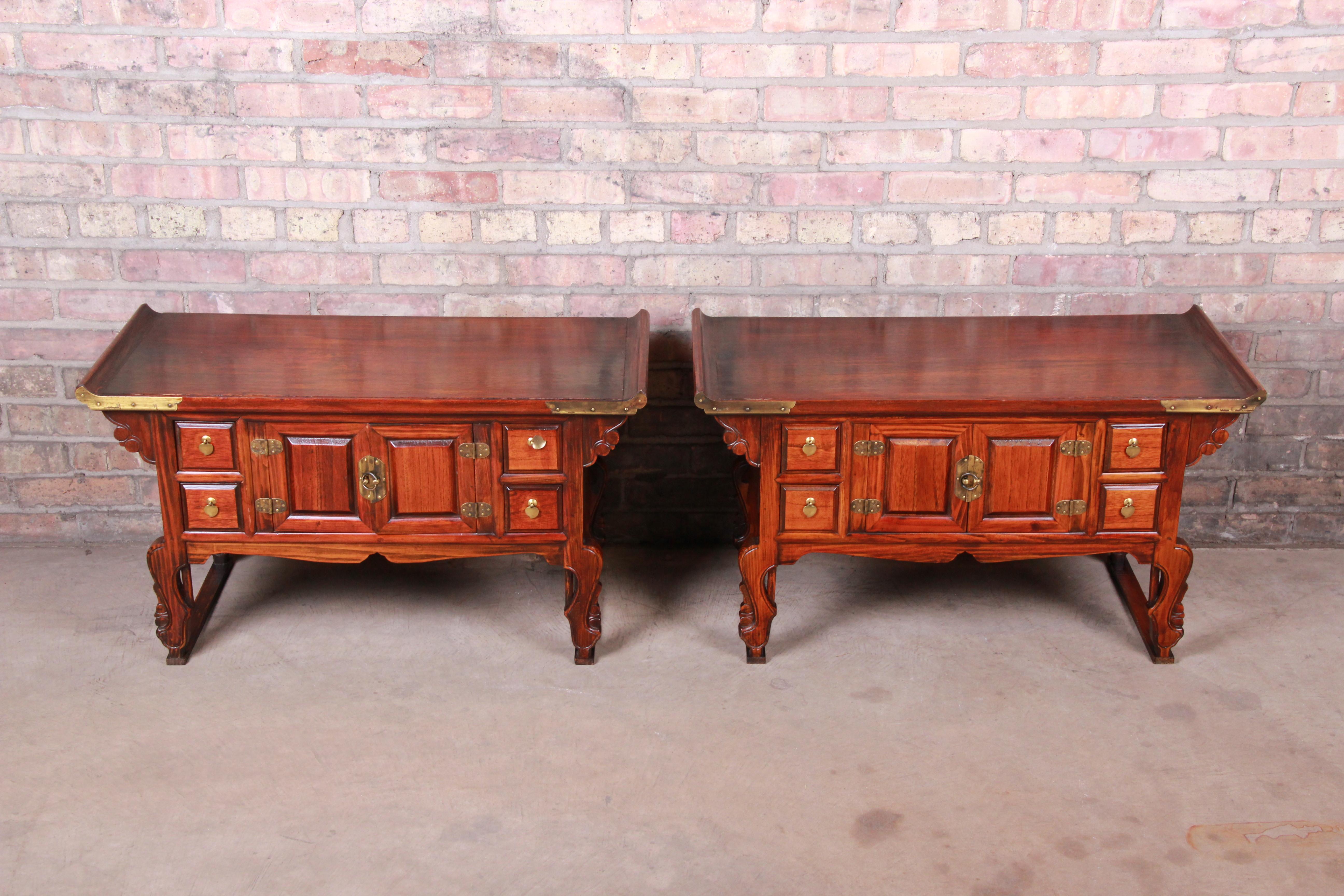 A gorgeous pair of Asian Hollywood Regency low nightstands or commodes

Korea, mid-20th century

Carved elm wood, with brass hardware and accents.

Measures: 33.25