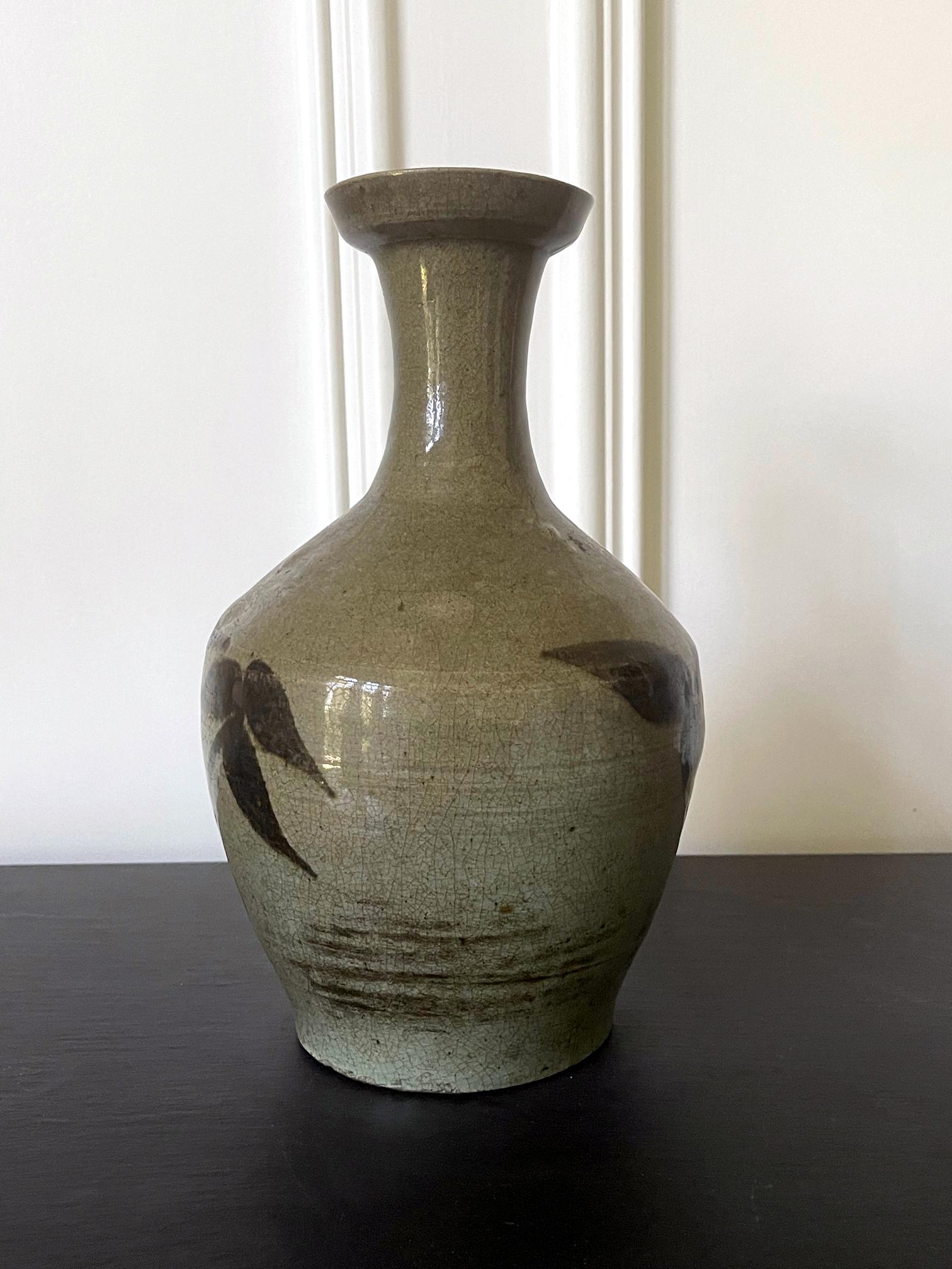 A wide-mouthed bottle form vase, known as Kwanggubyong, was a type of stoneware with celadon glaze, from Korea late Goryeo Dynasty circa 14-15th century. The untraditional shape and the decorative style and technique indicate that it was a