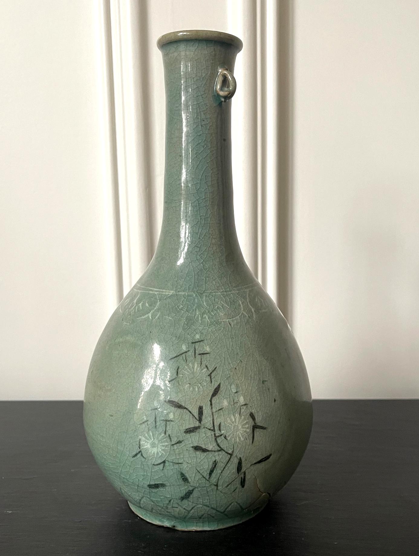 A Korean ceramic celadon bottle vase with inlay design from Goryeo Dynasty (918 to 1392AD) circa 12th century. With an elongated neck that continues down to the pear-shape body in smooth and elegant curve, and an applied lug on one side of the neck,