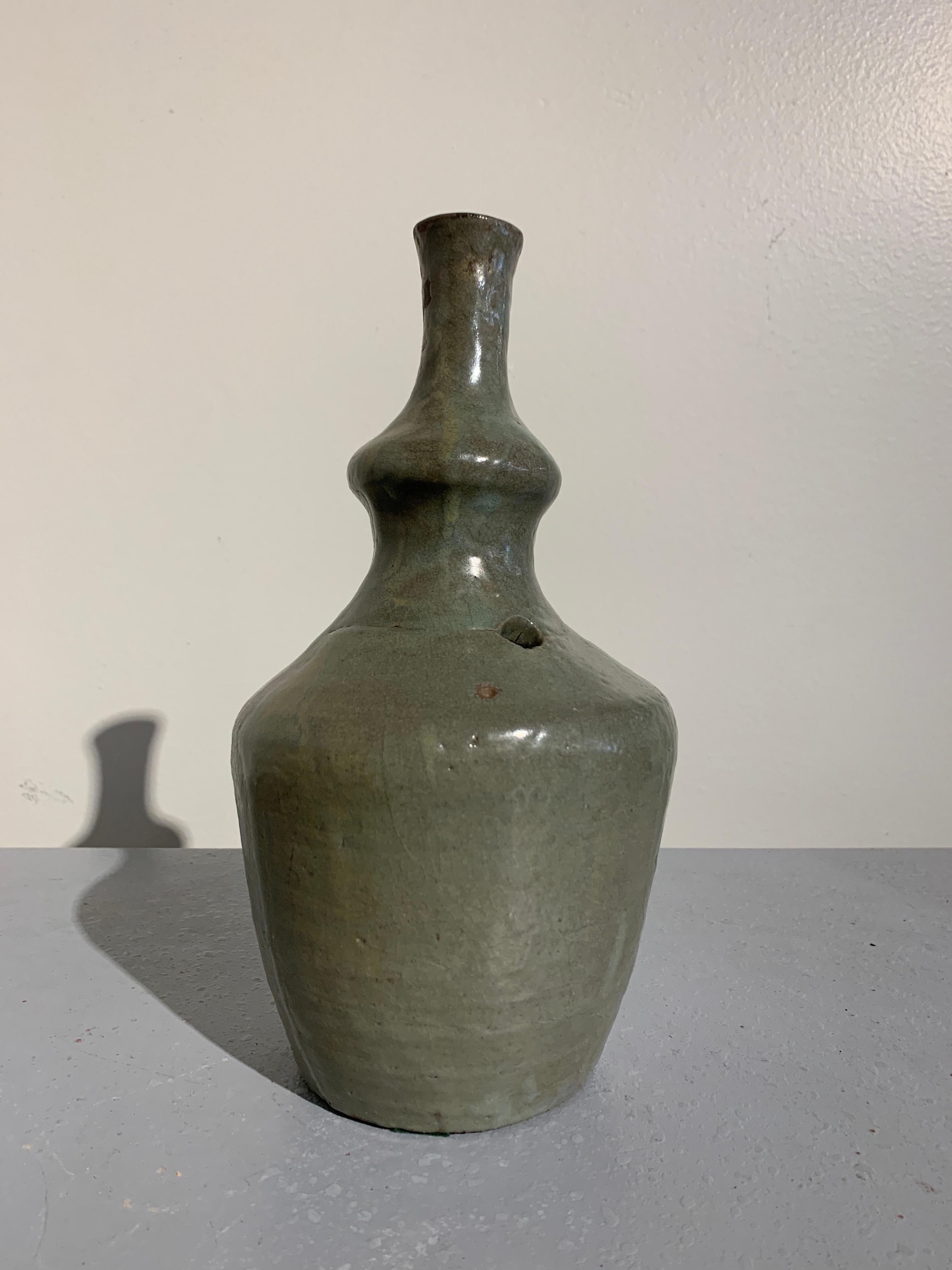 An understated and very heavily potted celadon glazed Korean ritual ewer or water sprinkler, kundinka, Goryeo Dynasty, 13th-14th century. 

The unusual bottle vessel, used as a water sprinkler for Buddhist rituals, is crafted of a heavy stoneware