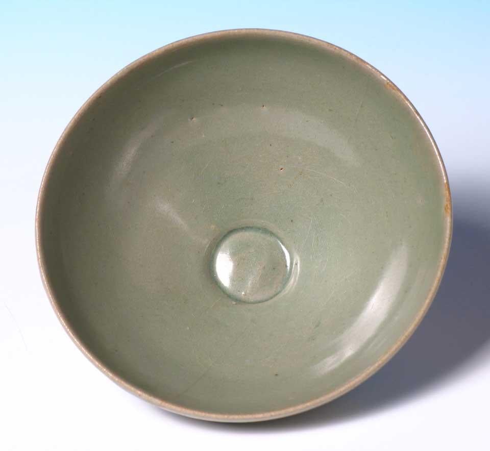 Korean celadon lotus bowl, a deep flared form on a narrow footed base, the exterior carved in lotus petal design and covered in a sea green crackled glaze with spur marks and kiln grit on the base. 
One minor crack emanating from the rim and