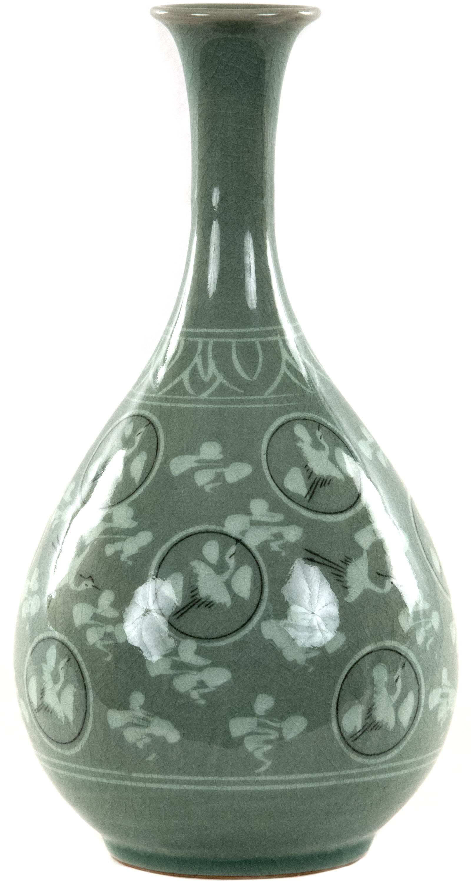 A Korean vase with a celadon craquelure glaze with a flared rim above an elongated neck tapering into a pear-shaped body decorated with motifs of flying white cranes and clouds, the 