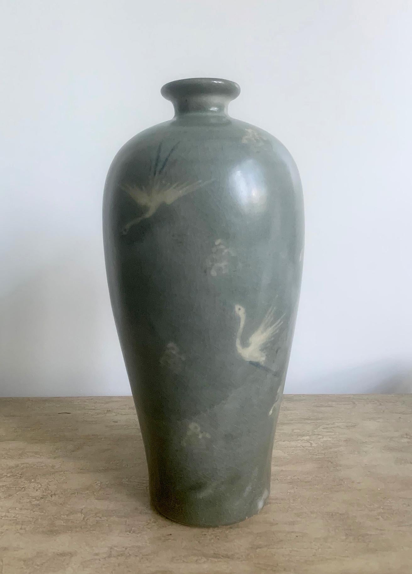 A stoneware vase in class Meiping form, known in Korea as Maebyeong. The vase was traditionally used to hold Plum wine and also the branches of plum blossom in season. The celadon vase feature black and white slip inlays that depicts cranes in