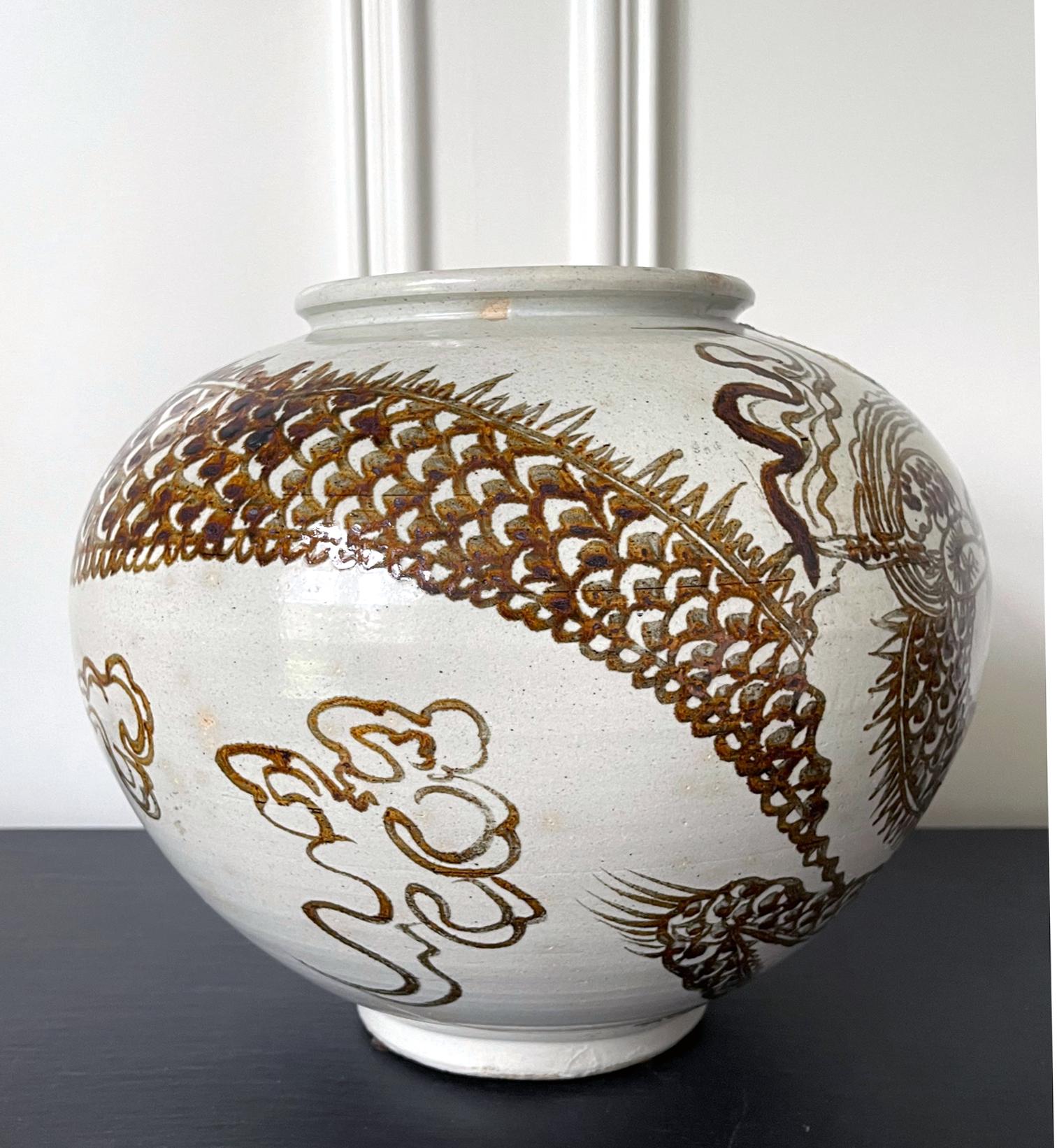 On offer is a large Korean ceramic storage jar (hangari) with white glaze and iron red underglaze dragon design. The globular shaped jar derived its form from the Moon Jar of the early Joseon dynasty, which were fused with two hemispheres and mostly