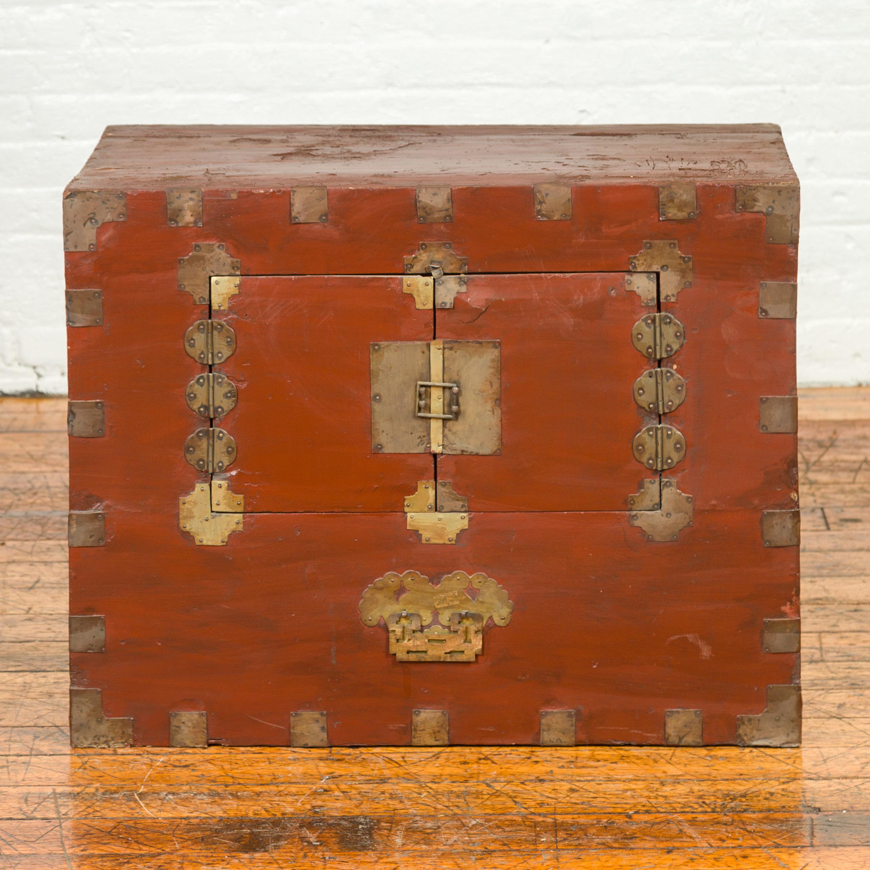 An antique Korean side chest from the early 20th century, with petite double doors and traditional brass hardware. Crafted in Korea during the early years of the 20th century, this side cabinet features a linear silhouette perfectly accented with