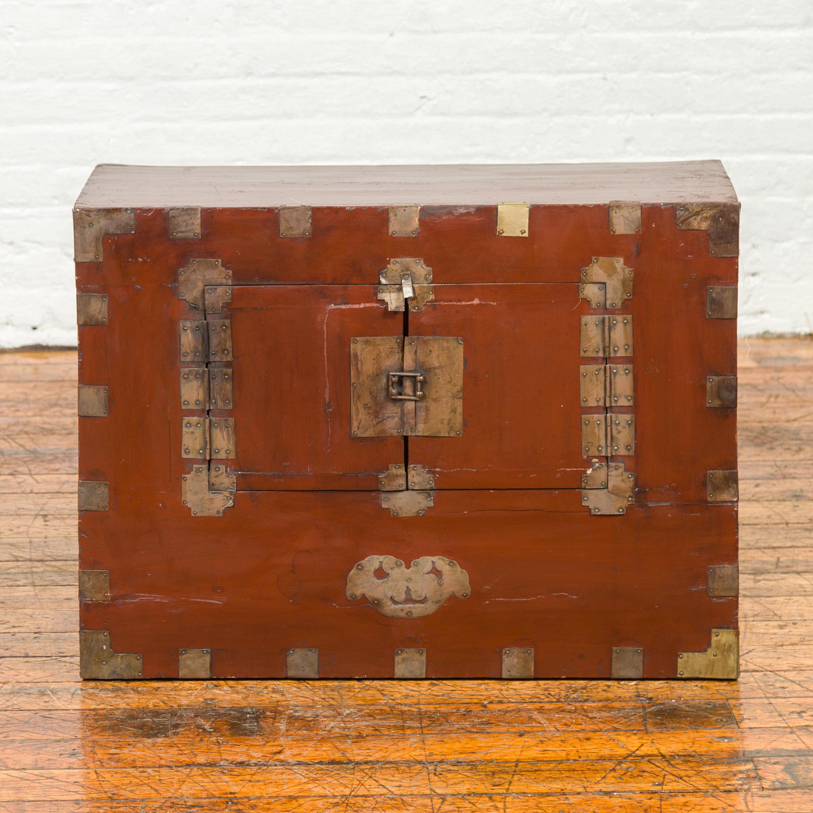 An antique Korean side chest from the early 20th century, with petite double doors and traditional brass hardware. Crafted in Korea in the early 20th century, this antique side chest marries form with function in an exquisite display of traditional