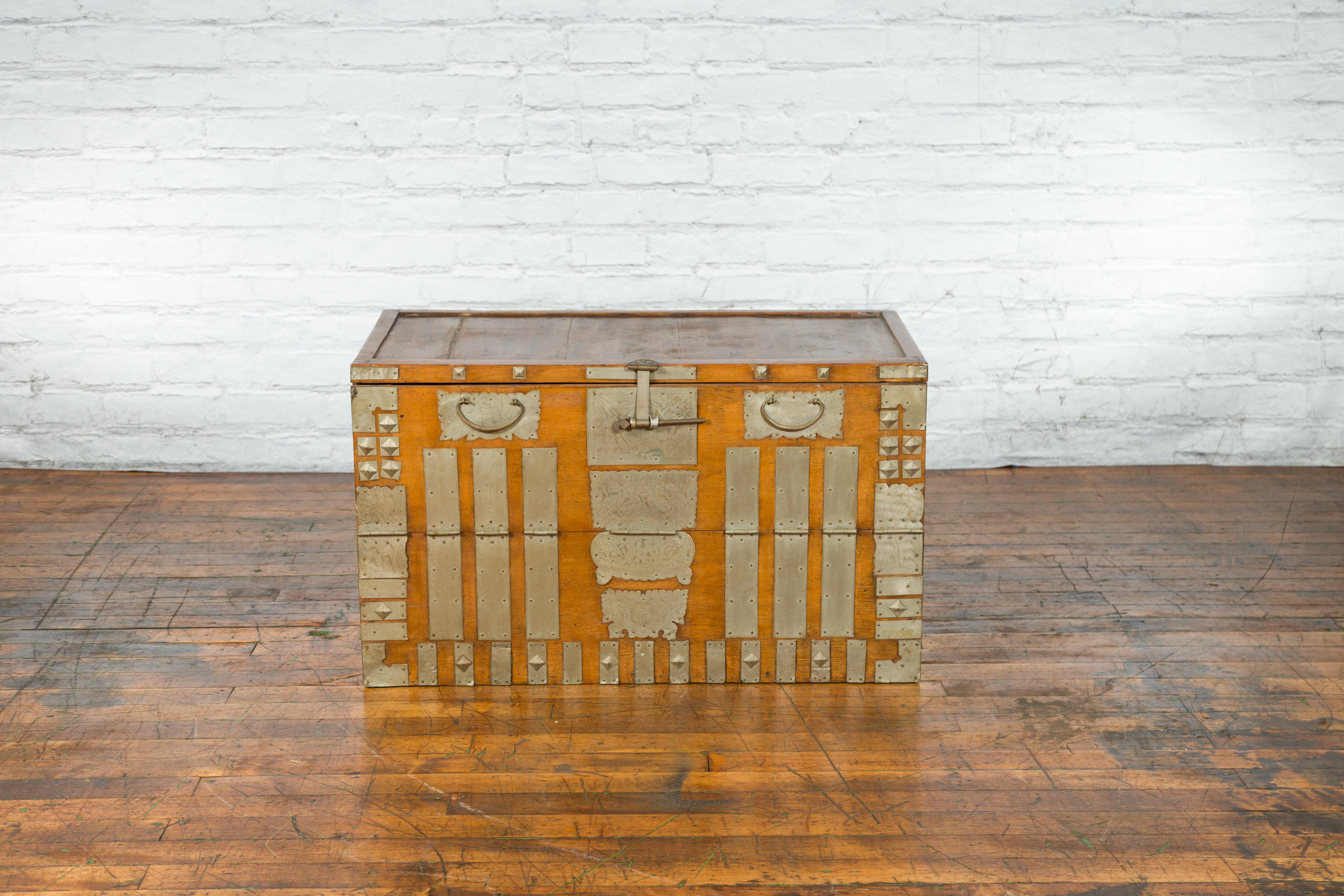 An antique Korean storage chest from the early 20th century, with silver plated brass hardware and drop down panel. Created in Korea during the early years of the 20th century, this storage chest features a light brown structure beautifully accented