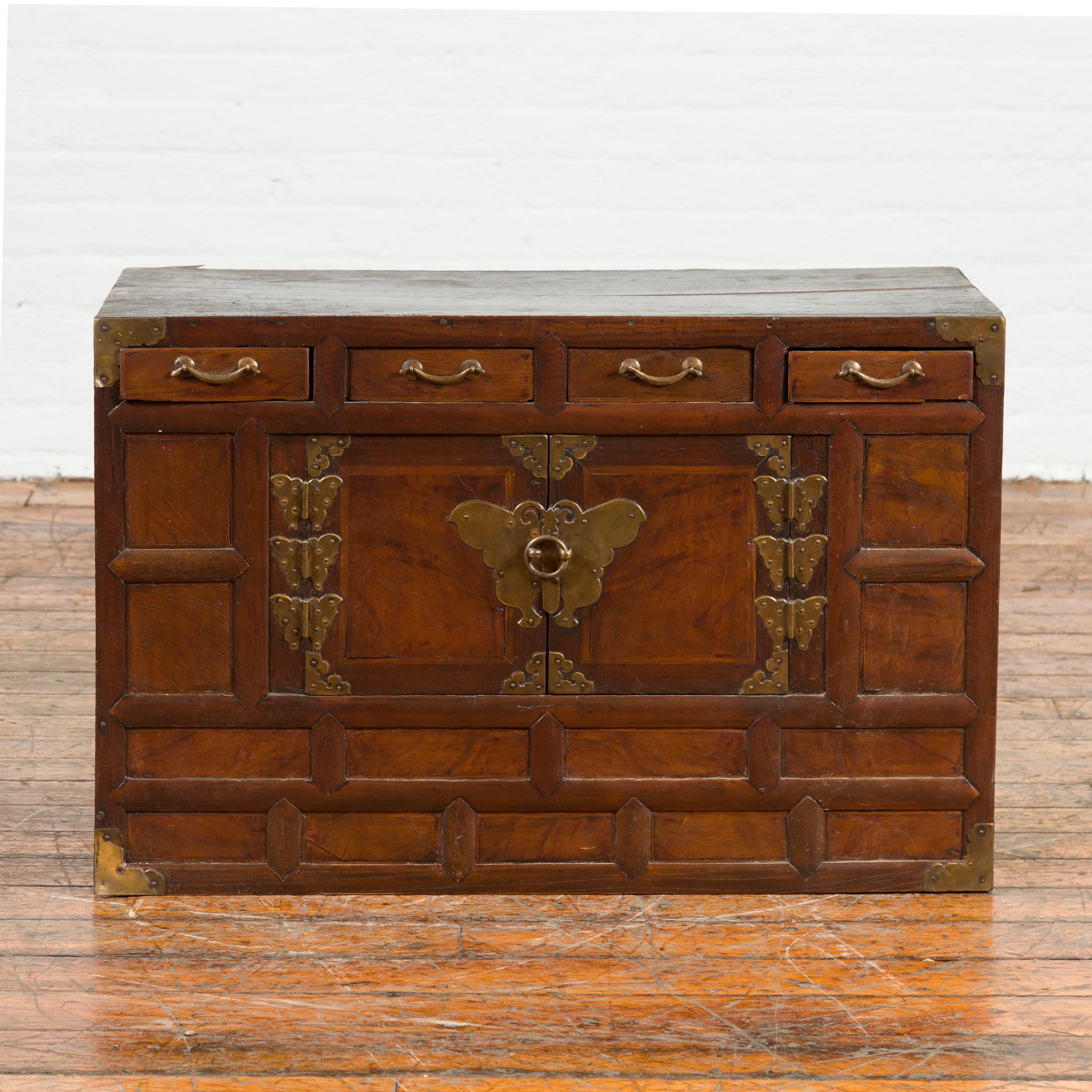 A Korean antique side chest from the early 20th century, with brass butterfly hardware, petite double doors and drawers. Created in Korea during the early years of the 20th century, this small cabinet features a rectangular top sitting above a