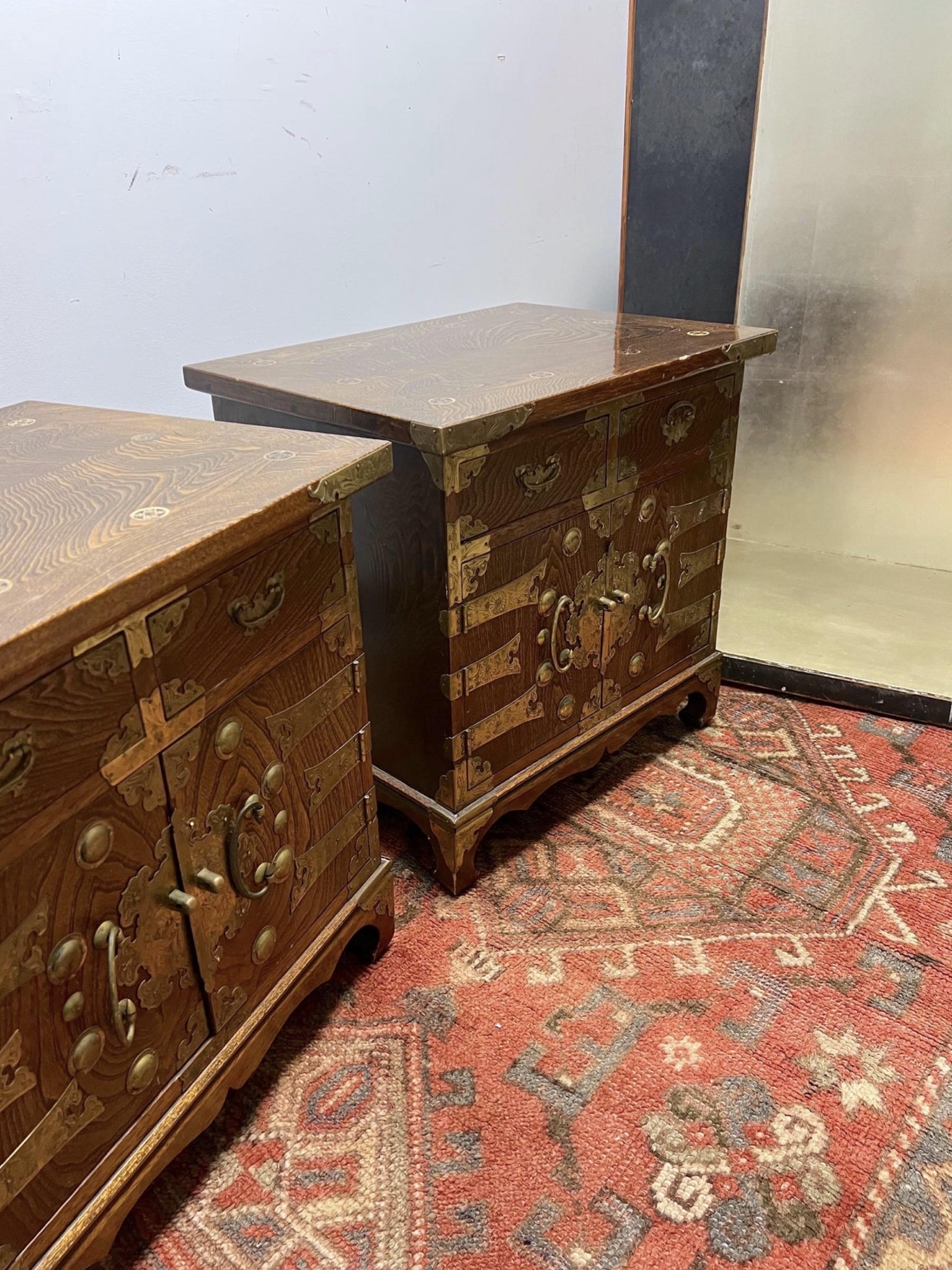 A fantastic pair of antique Chinese Tansu end table or nightstands. They have brass inlay on the tops and nice brass hardware. These solid wood chests have 2 drawers above a 2 door cabinet.