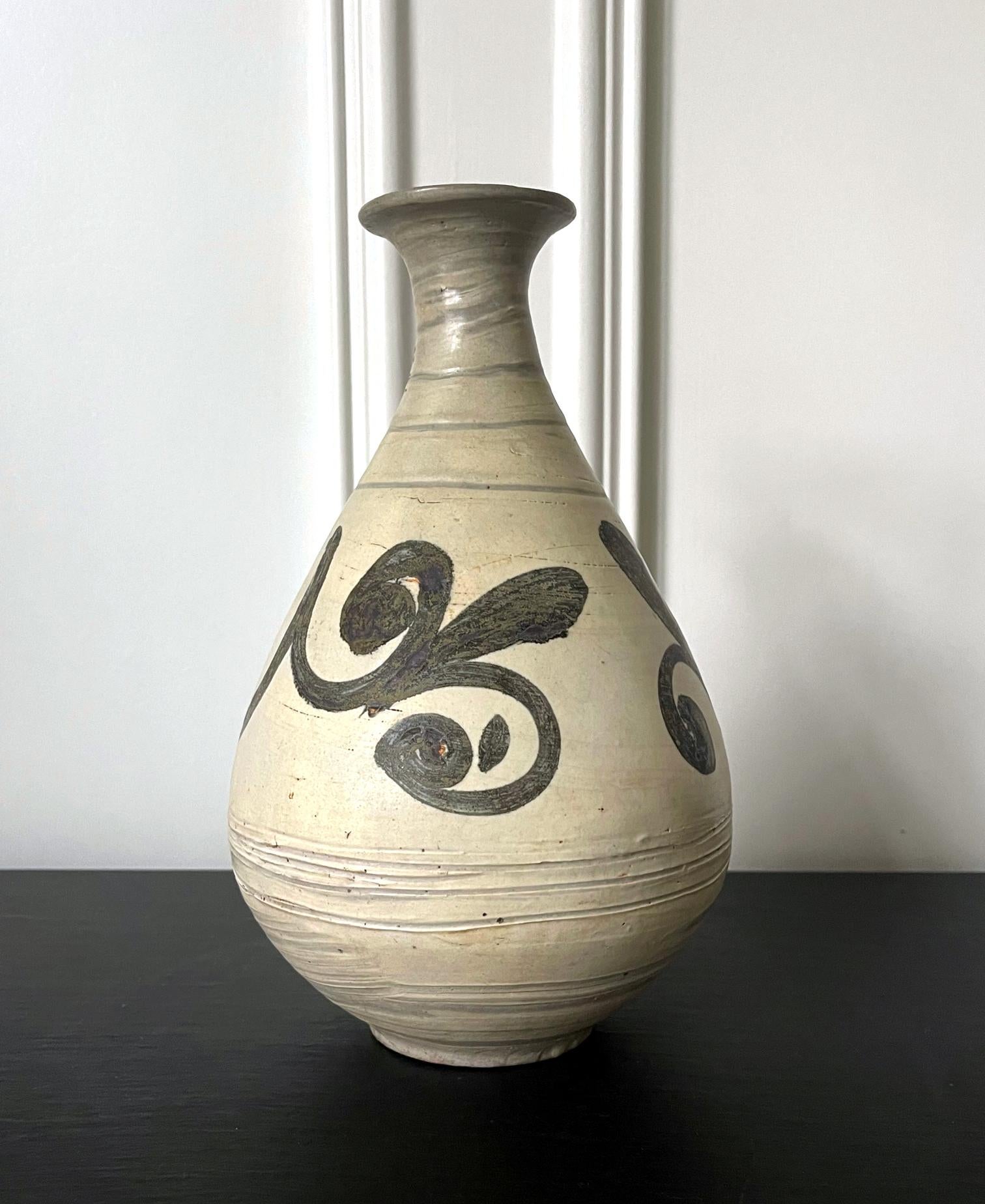 An antique Korean Buncheong stoneware vase from early Joseon Dynasty circa late 15th to early 16th century. The vase is of a classic pear form with a waisted neck and a flared mouth. The generous body is supported by a ringed base. The surface is