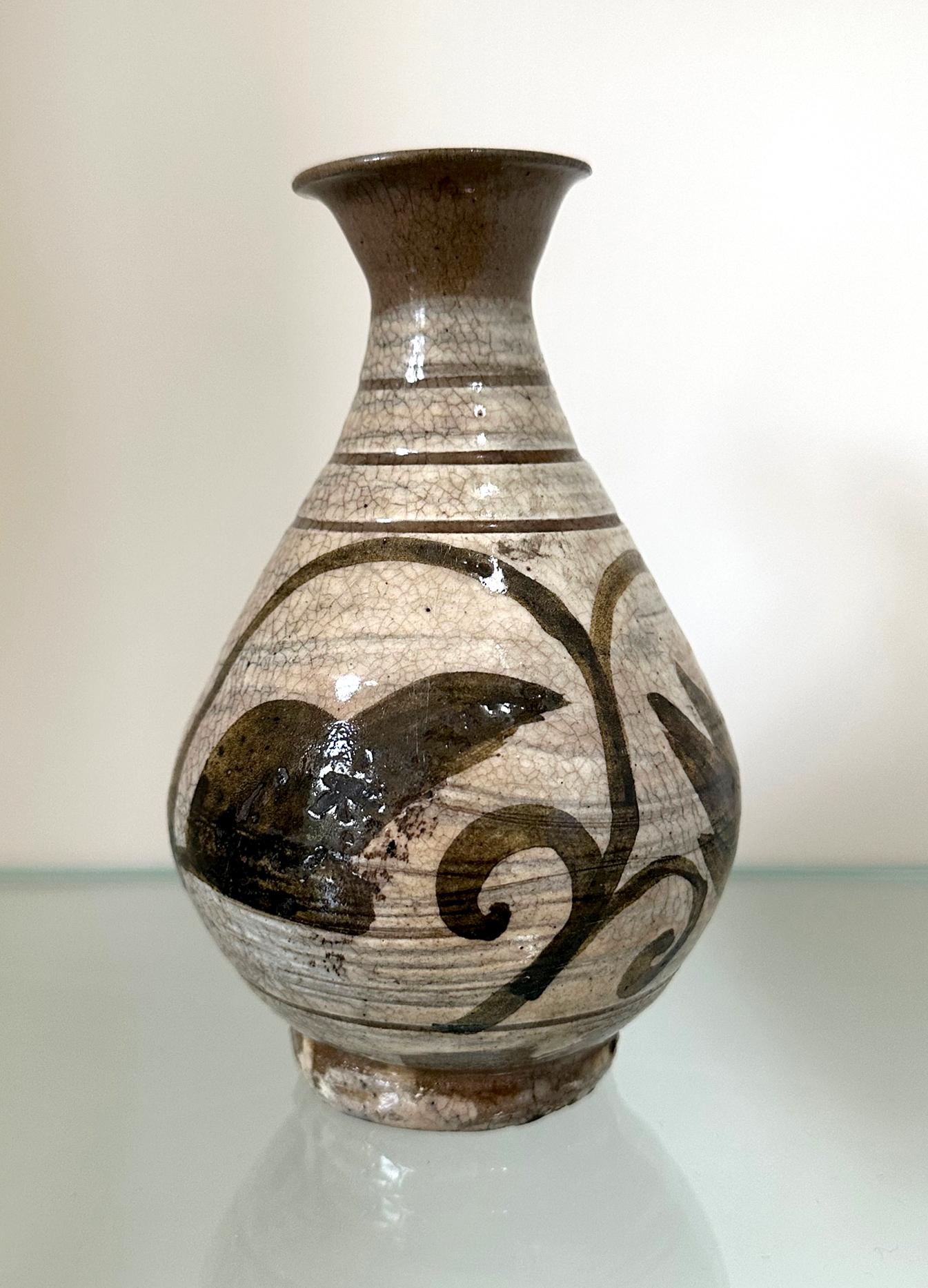 A small antique Korean Buncheong stoneware vase from early Joseon Dynasty circa 16th century. The vase is of a classic pear form with a waisted neck, a flared mouth and a ringed base. It is slightly irregular in shape, typical of the stoneware from