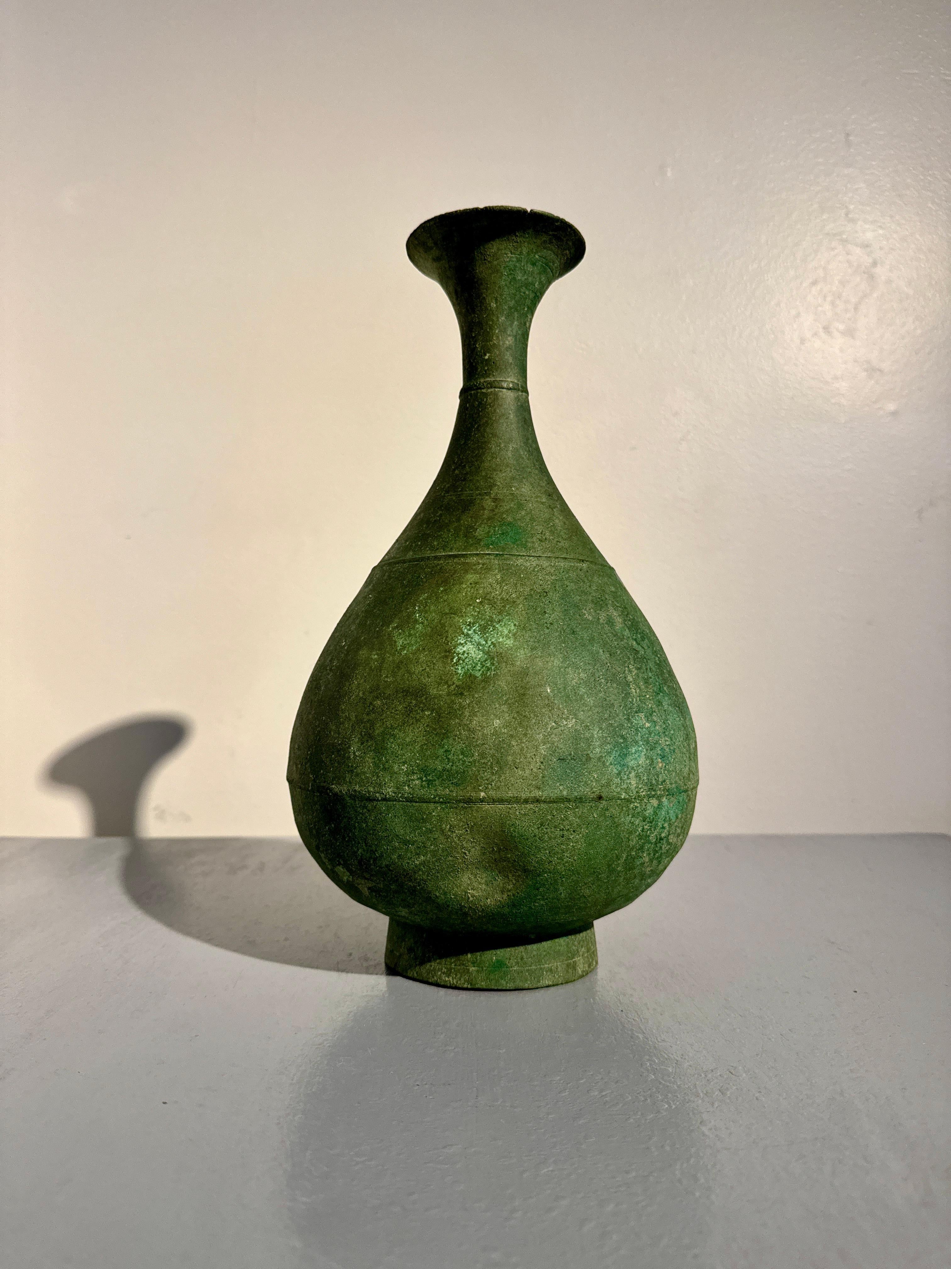 An elegant and unusually large Korean Goryeo bronze bottle vase with green patina, Goryeo Dynasty, 12th/13th century, Korea.

The graceful vase of typical bottle form, with a bulbous body set upon a short ring foot. The round body tapers upwards to