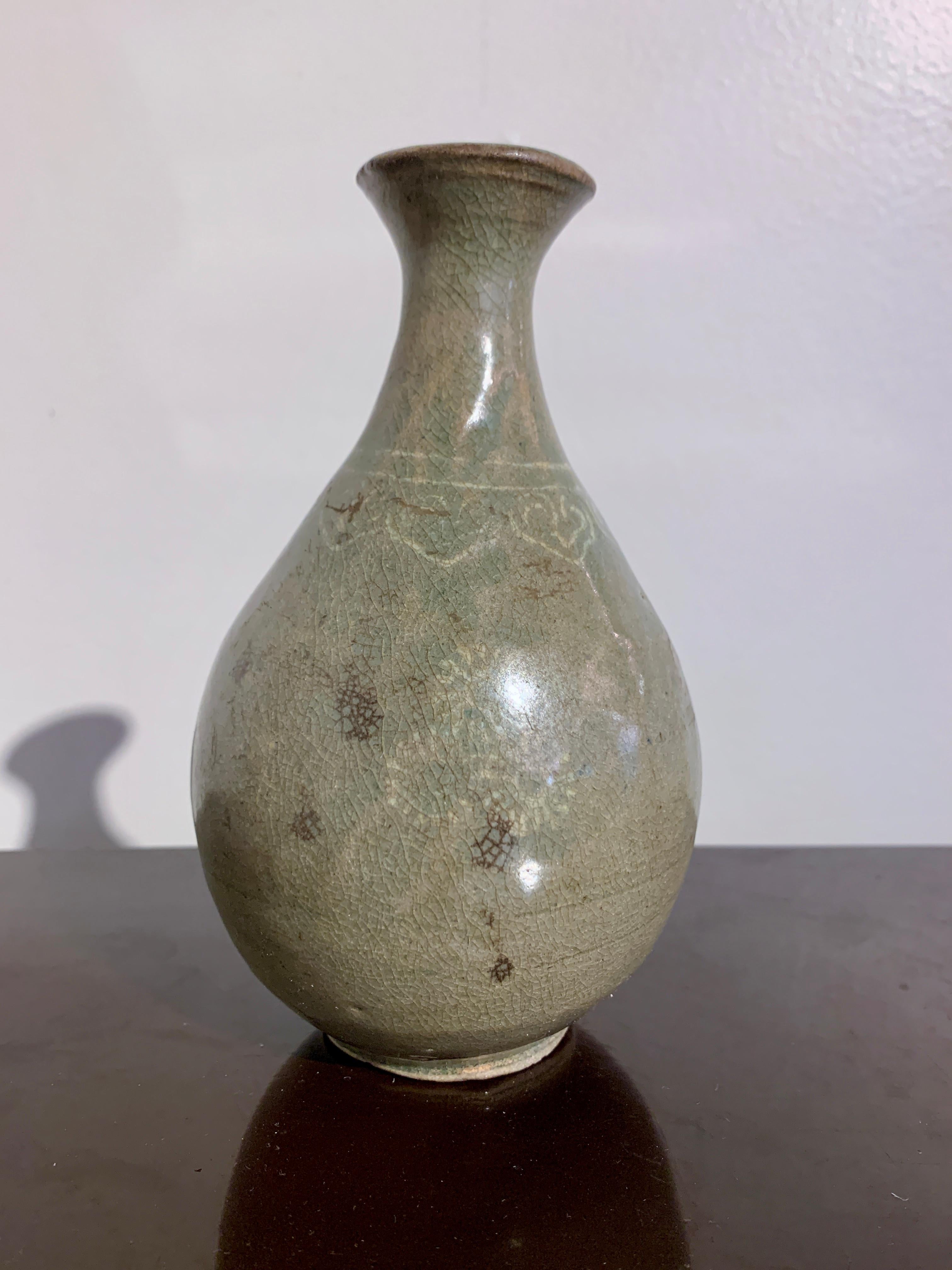 A delightful small Korean Goryeo ware celadon glazed stoneware bottle vase with sangam slip inlay, Goryeo Dynasty, 12th - 13th century, Korea.

The small bottle vase of typical form and crafted from a porcelaneous stoneware with a pear shaped
