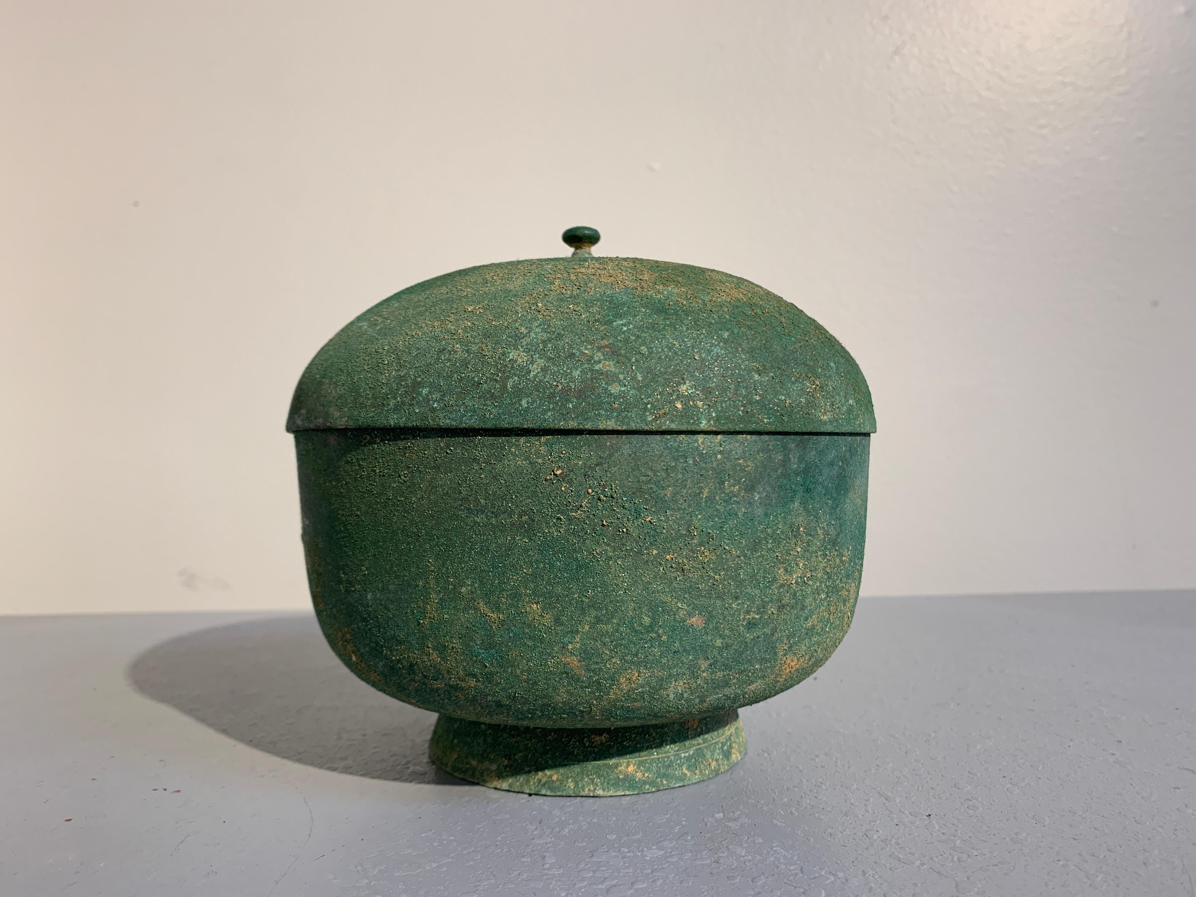 A fine Korean spun bronze bowl and cover with nice malachite green patina, Goryeo Dynasty, 13th century.

The simple bowl of nearly globular form, with a short, slightly splayed foot, wide body, and domed lid topped with a small knob finial. The