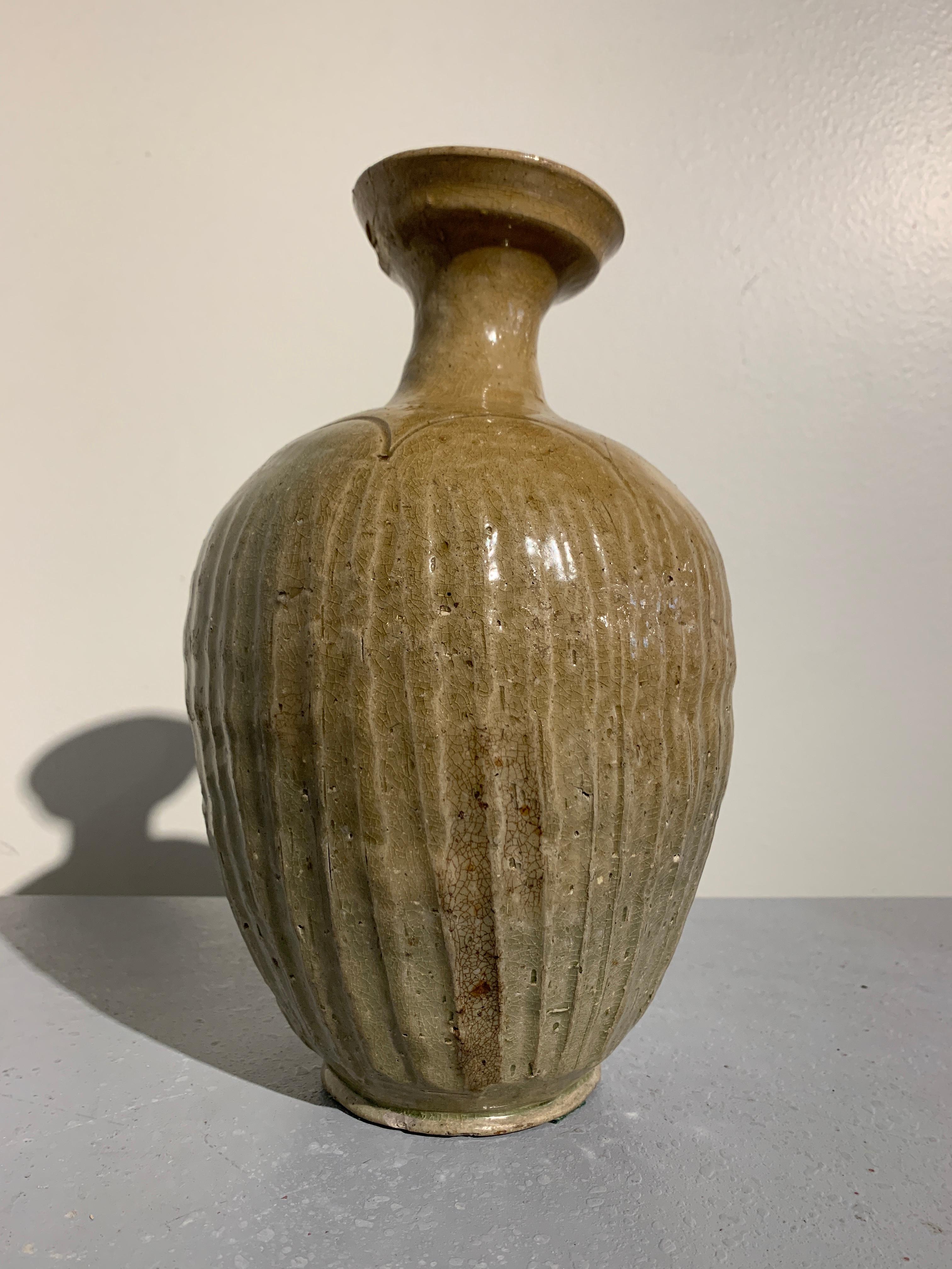 A wonderful early Korean Goryeo (Koryo) Dynasty celadon glazed stoneware bottle vase with ribbed body and cup mouth, late 11th-early 12th century, Korea.

The bottle vase, originally for serving wine, features an ovoid body with distinct, vertical