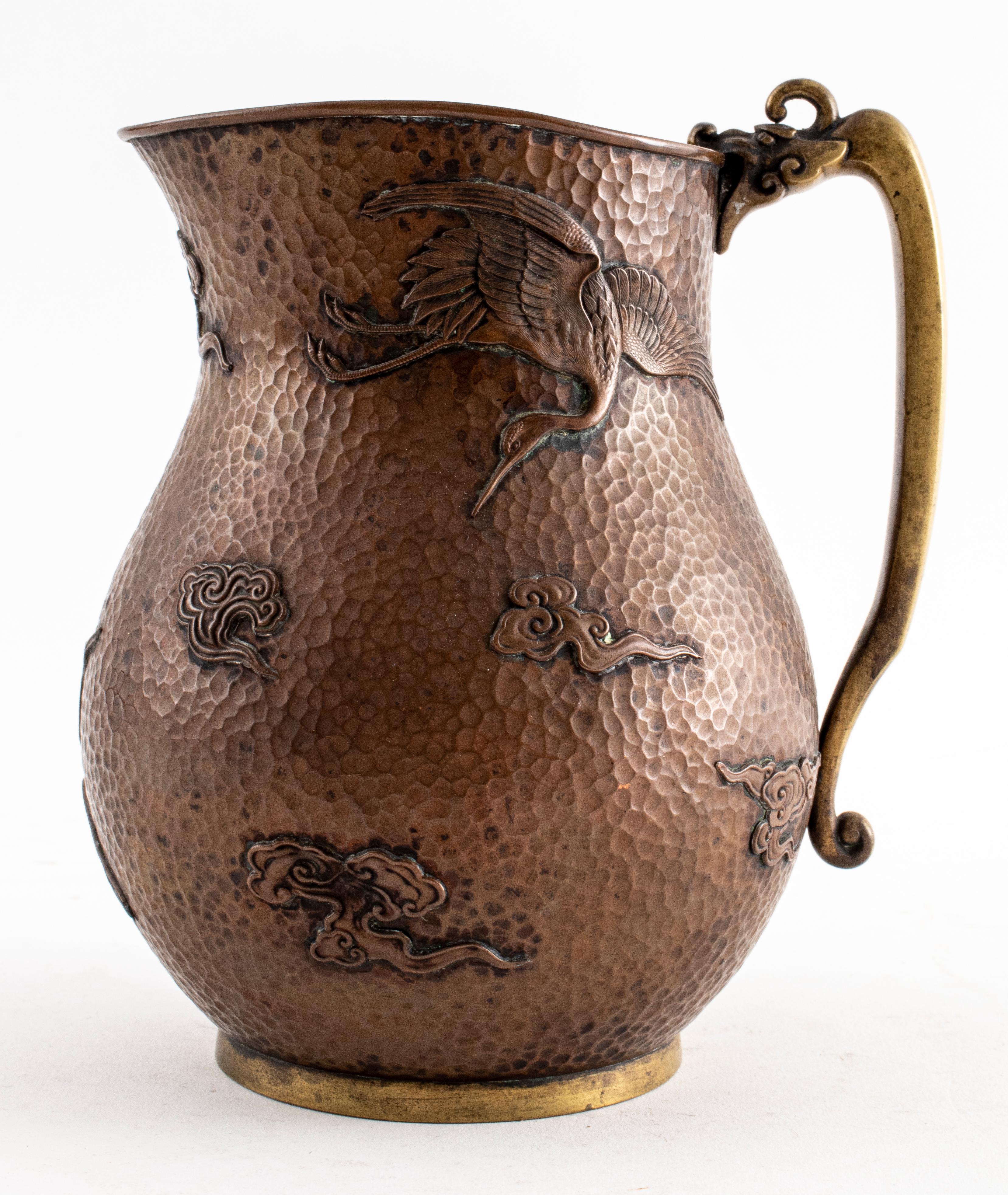 Korean hammered mixed metal pitcher with crane and cloud motifs raised in relief with a dragon-head handle. Measures: 6.75