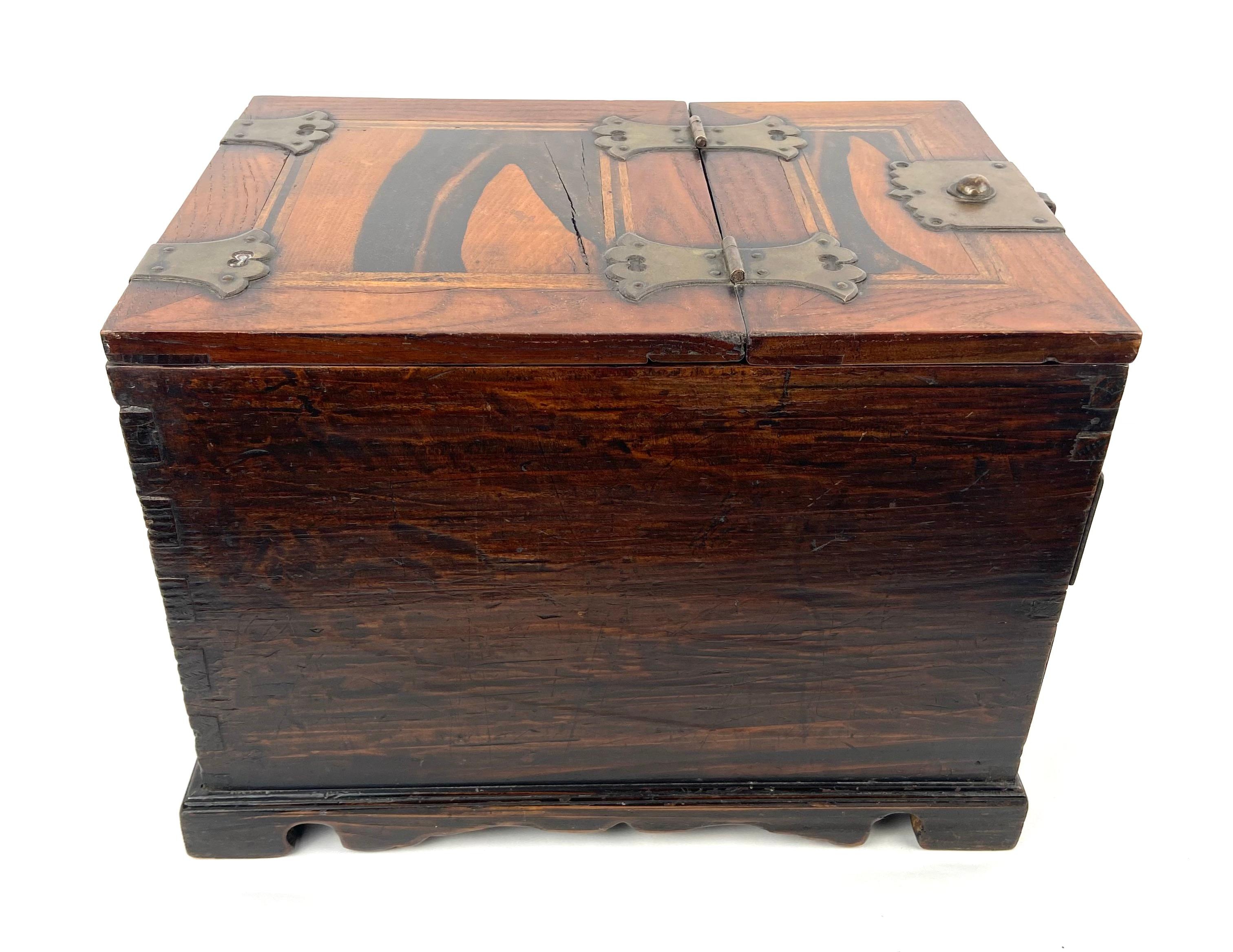 Korean jewelry box in exotic persimmon or kaki wood and brass.  
The box has 2 drawers and on top a flap that serves as a folding mirror.