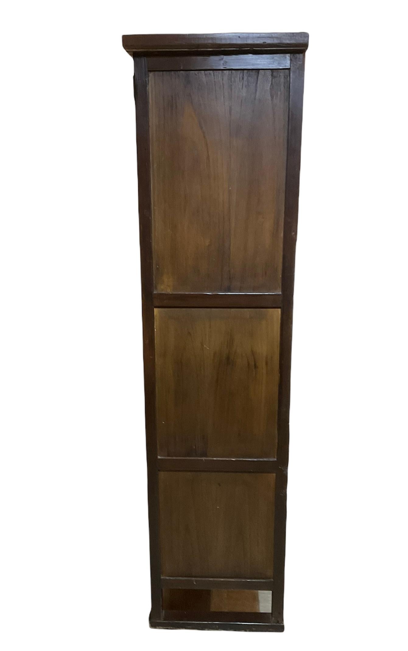 This is a Korean large wood cabinet/chest. The cabinet has two drawers at the top with C-shaped iron handles and below it, there are 3 compartments. They go from the biggest to the smallest one. Each one has hinged doors decorated with iron round