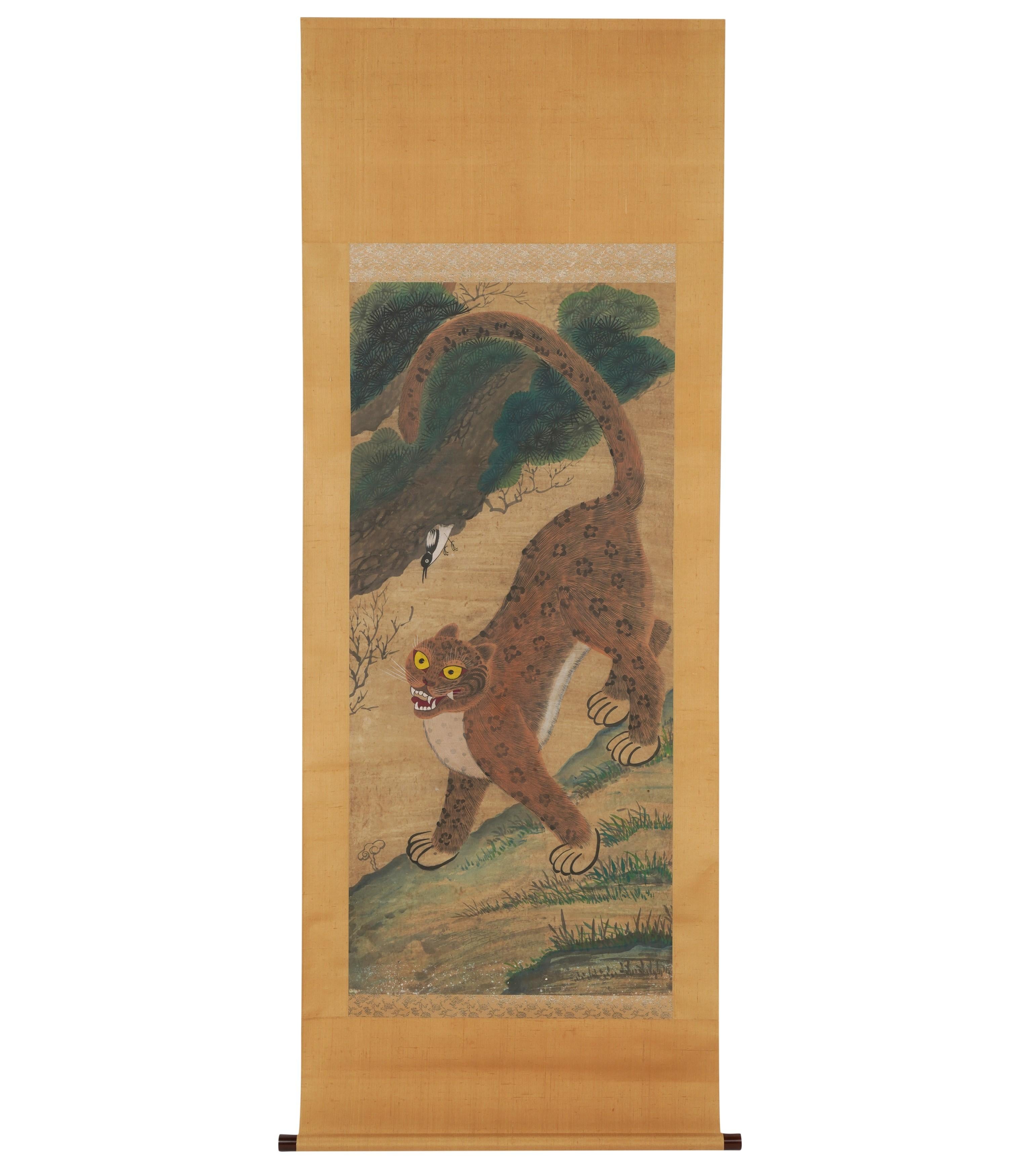 A wonderfully painted and detailed Korean folk art Minhwa Jakhodo (The letters “jak” means magpie; “ho” means tiger; and “do” means painting) Tiger and Magpie Scroll Painting. The piece is hand-painted on silk and mounted with a brocade border and