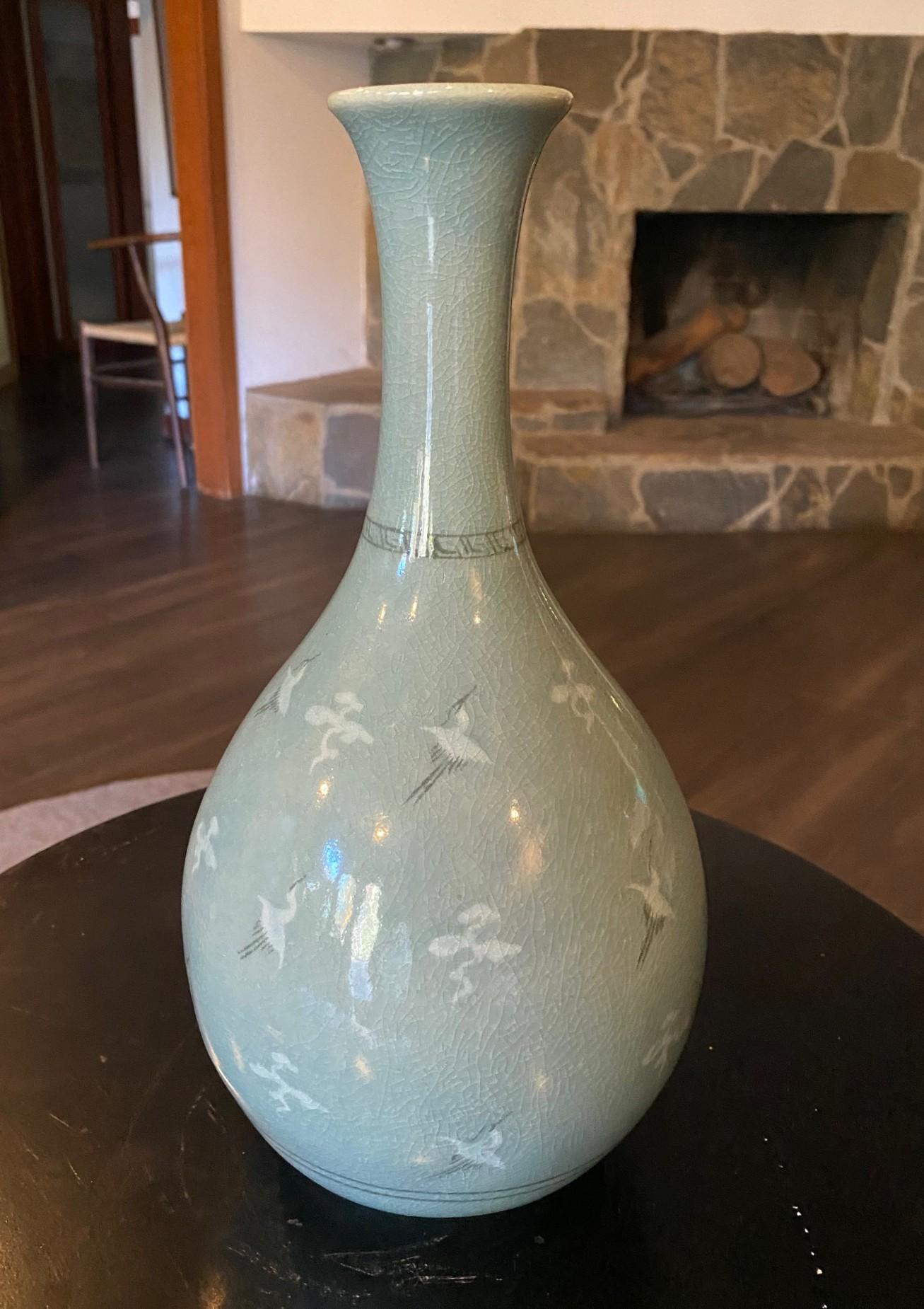 A beautifully colored and decorated bird motif (with cranes or egrets) Korean crackle glazed celedon vase.  The piece radiates in the light and shifts colors between green and blue depending on the angle of illumination (you can see the color change