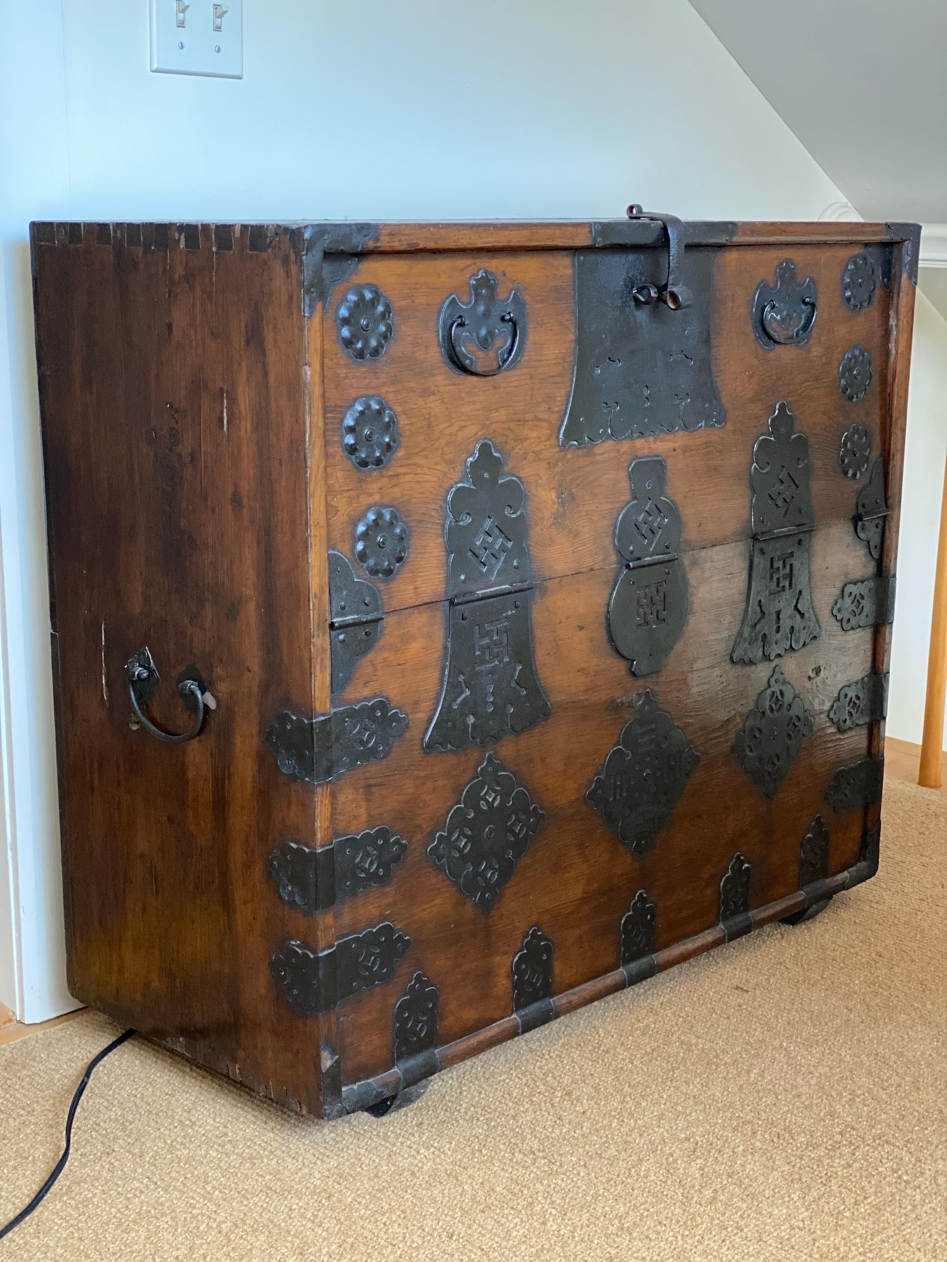 Korean Tansu Elmwood Chest with Iron Hardware, 20th Century
This elegant Korean Tansu Bandaji, more commonly known as a tallboy wedding chest or blanket chest, is constructed entirely of elmwood featuring ornate iron hardware, lock plates, and