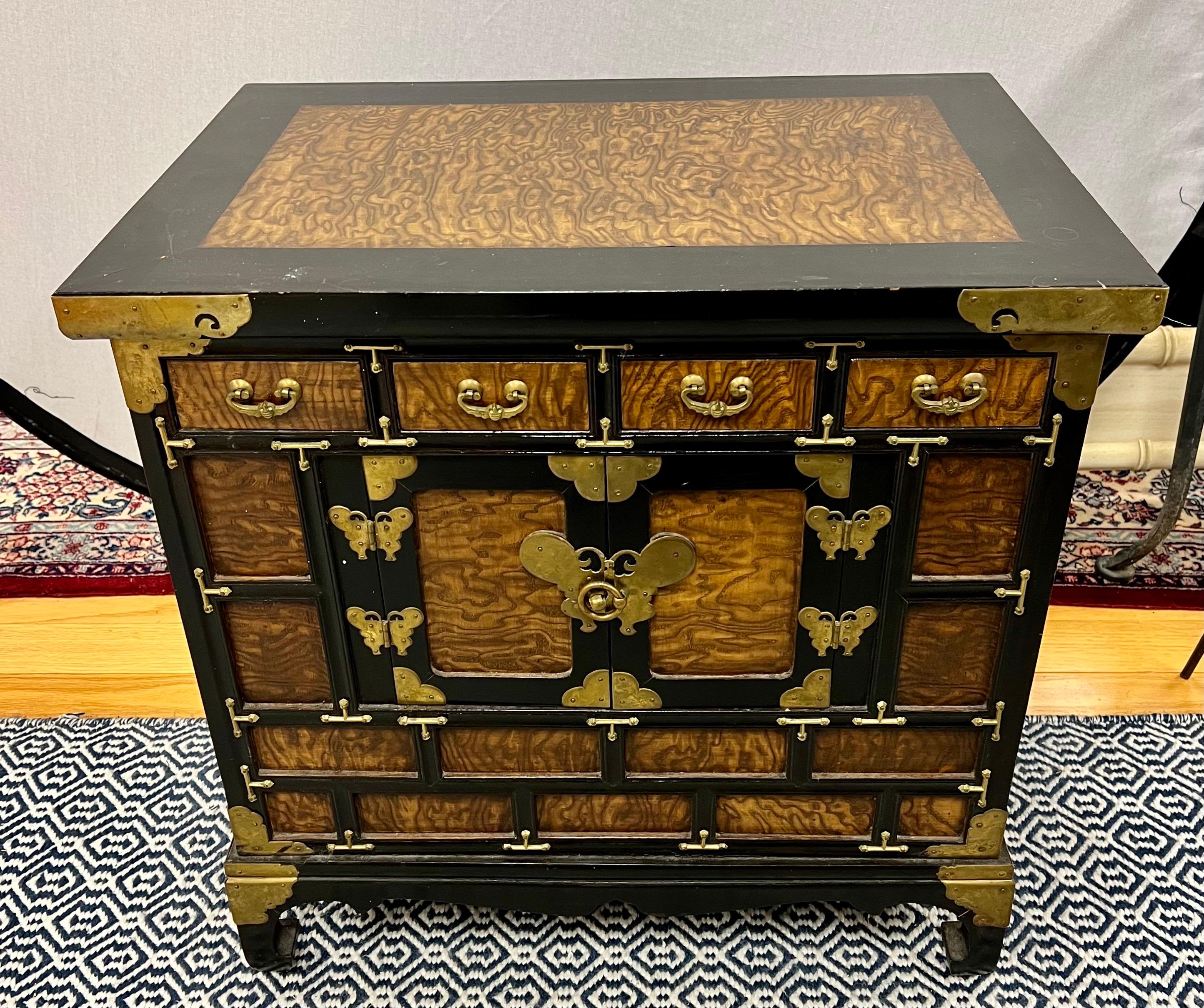 Asian scholar's chest configured with four upper drawers over lower cabinet. Beautifully appointed with striking brass butterfly hardware and hinges. Richly grained two-tone finish. Own the best.