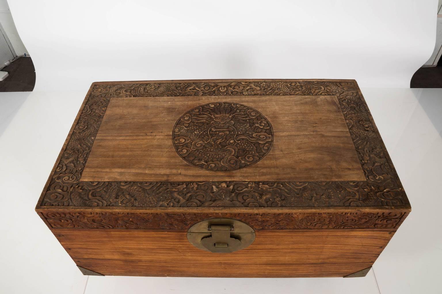 Carved Korean trunk with decorative shallow relief carvings that feature a centre dragon medallion on the lid with brass hardware, circa 1940.
 