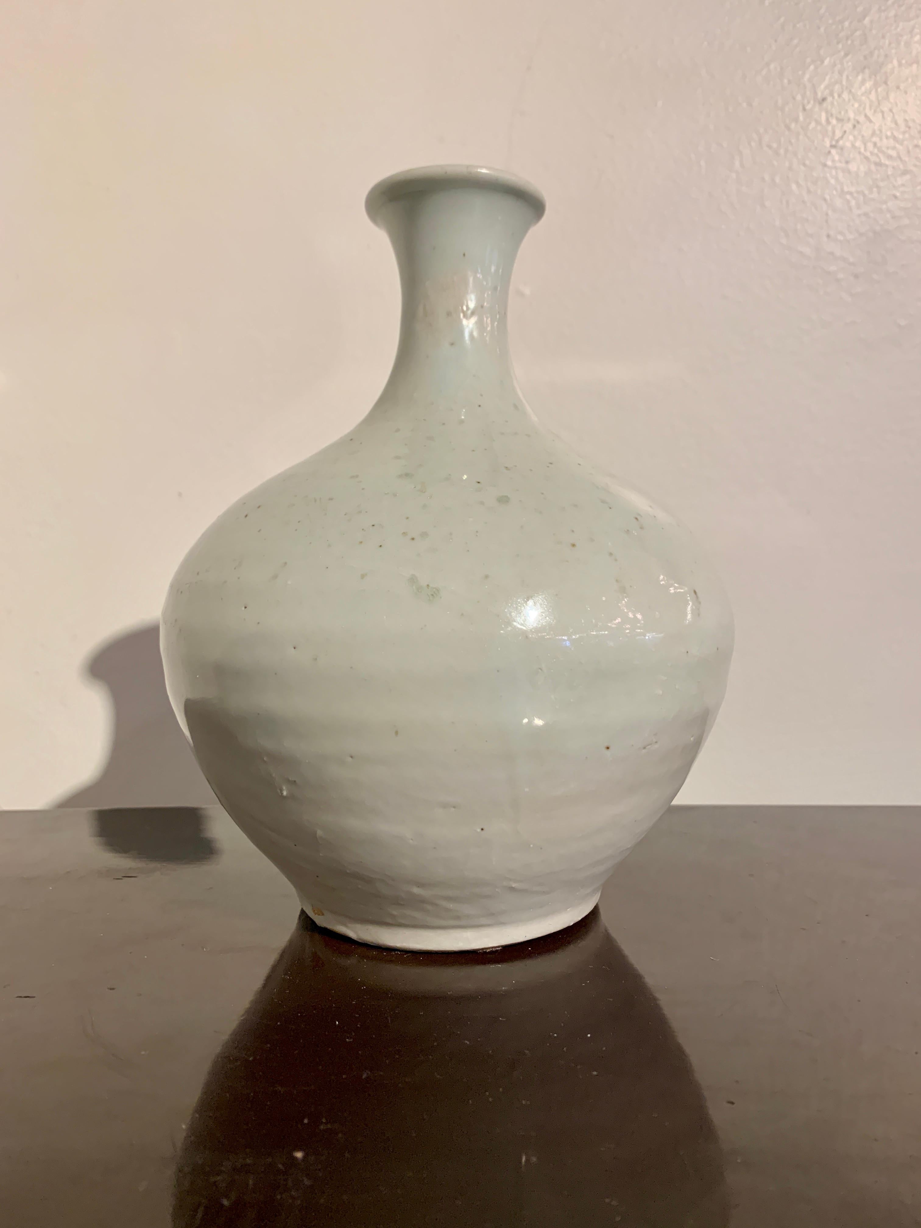 A subtle and elegant Korean Joseon Dynasty white glazed porcelain bottle vase, 19th century, Korea.

The bottle vase with an unusual globular body, narrow neck and slightly everted mouth, all set on a short ring foot. The vase heavily potted and