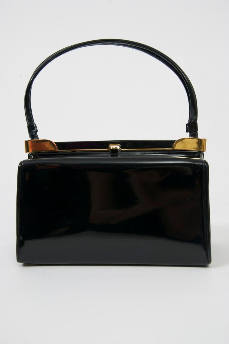 Koret produced some of America's best handbags in mid-century America, both in terms of design and quality. This example is crafted of black patent leather and features interesting brass hardware, lending an innovative twist to a classic style.