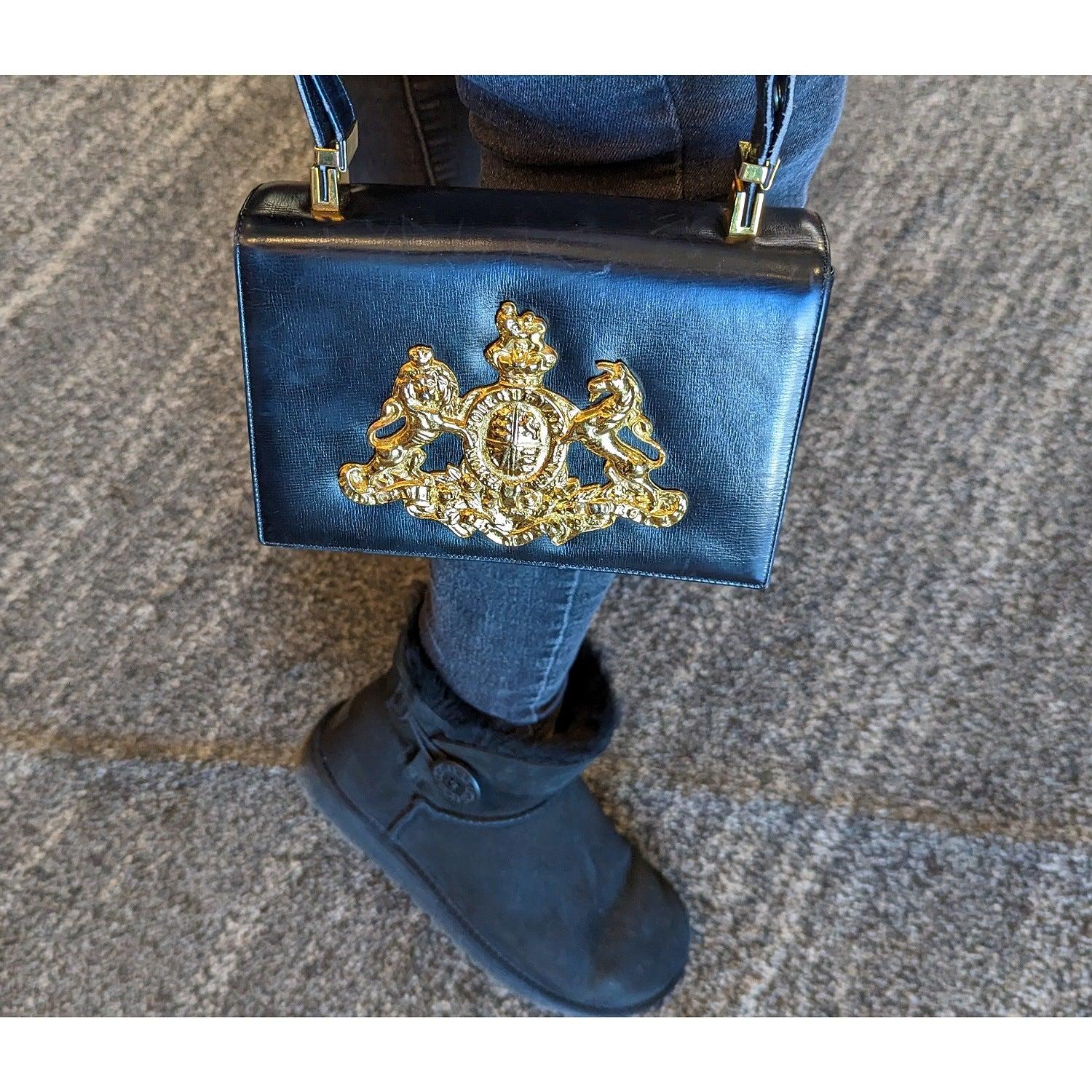 Amazing Calf black handbag by Koret! The handbag has an A-frame structure, with a rectangular silhouette and top handle. The handbag flap has a hidden snap closure, and the handle features gold-tone hinges. The interior of the handbag, with its