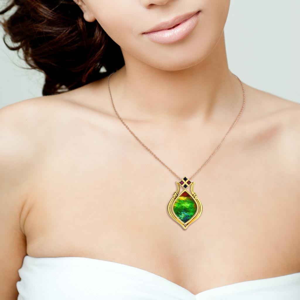 Designed by Korite this large Grand Princess ammolite pendant is a classic with stone of naturally captivating colors and layers of brilliant iridescence. This prehistoric gem is marquise cut set in 18k yellow gold with ruby and sapphire