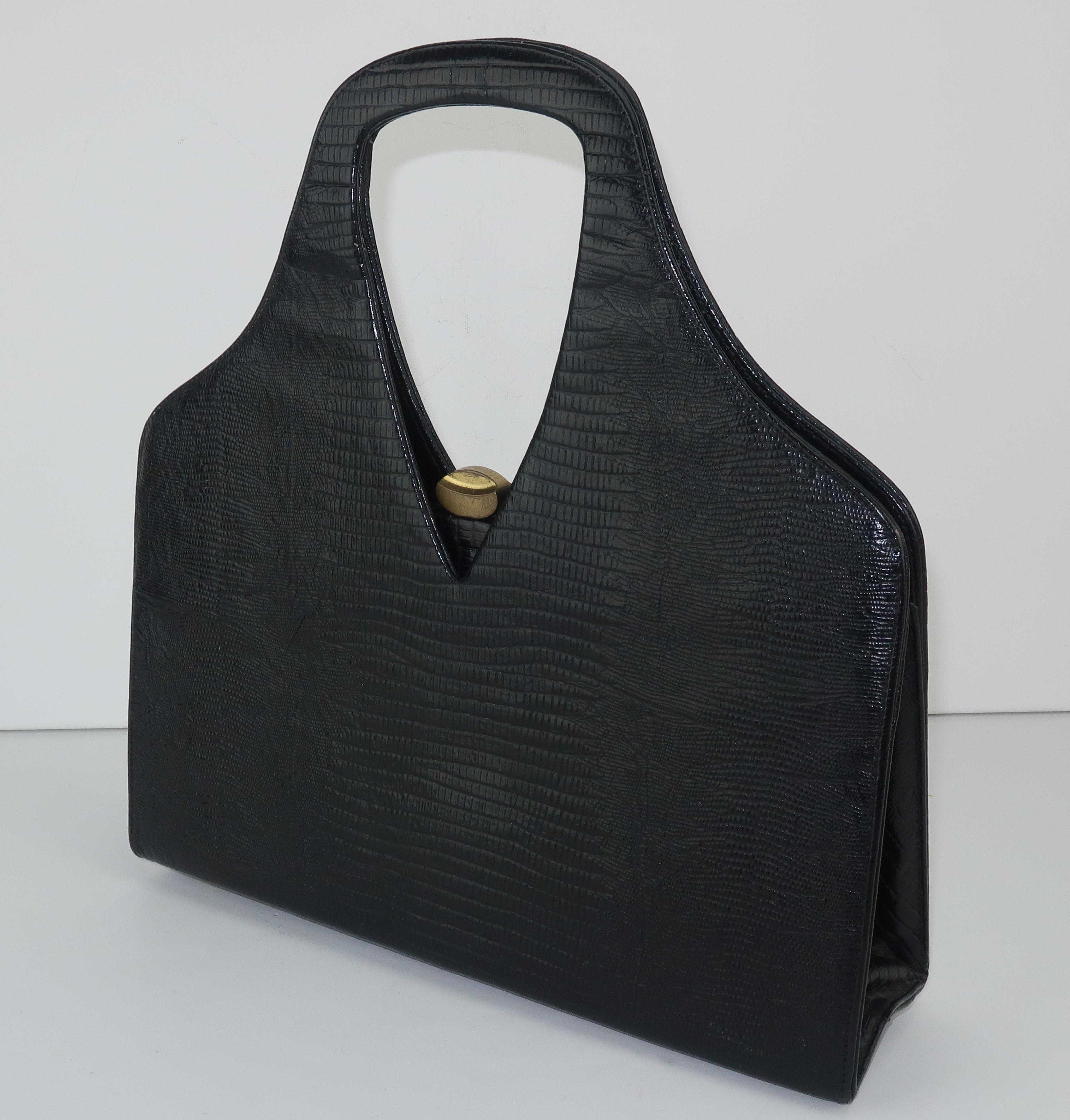 A 1950's black lizard skin handbag from Koro Creation with a unique top handle silhouette.  The push button brass closure opens to reveal a contrasting interior with two open side pockets and a matching mirror.  Brass feet at the base keeps this