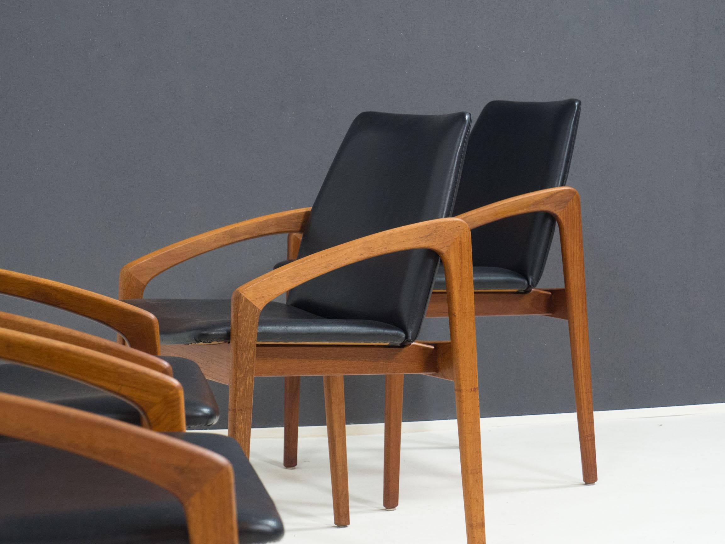 Set of four dining chairs, widely attributed as designed in the 1960s by Henning Kjærnulf for Korup Stolefabrik, Denmark.

These chairs are made from solid teak, and have a seat and back upholstered in its original black faux leather.

The
