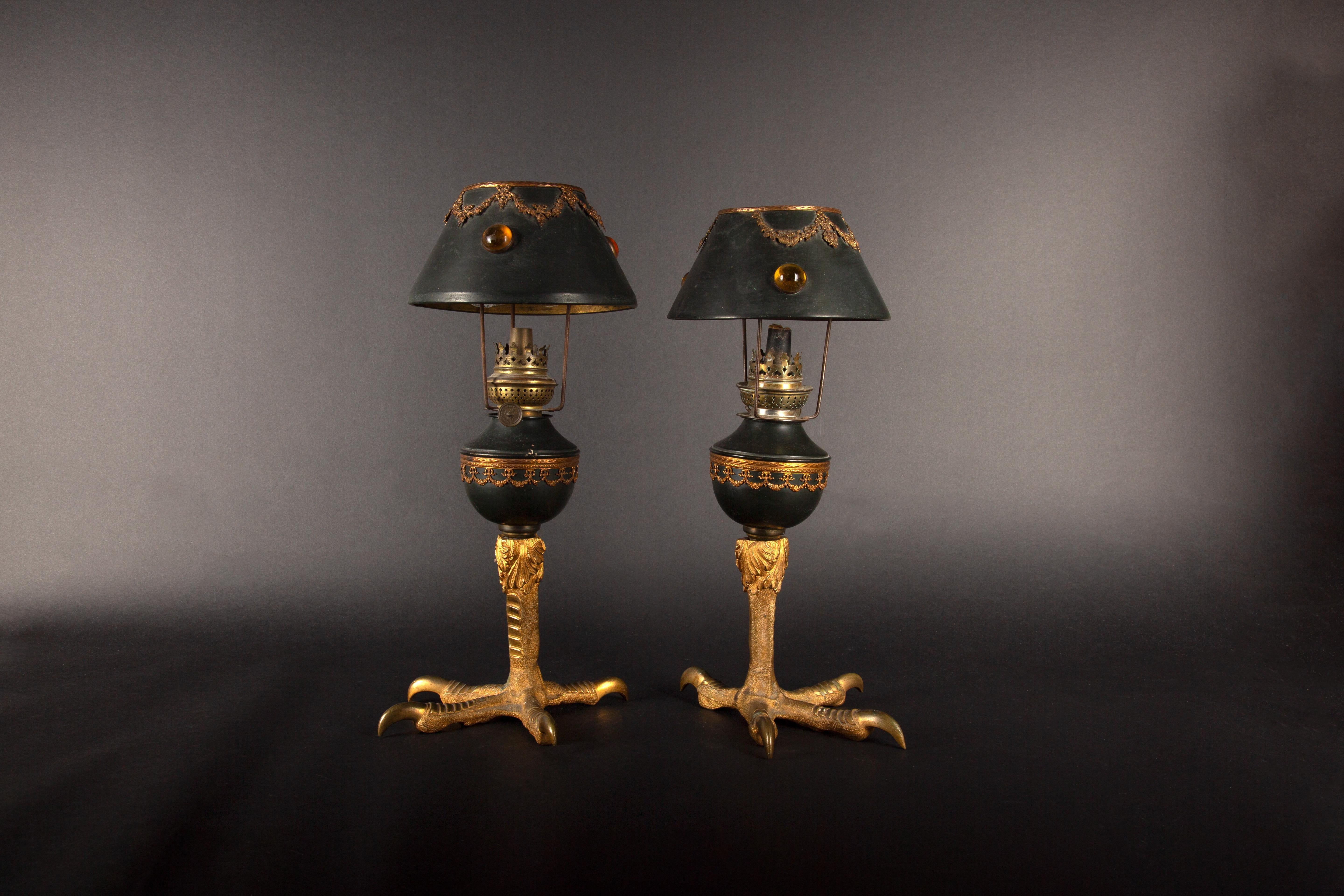 These captivating 19th-century French oil lamps exude an air of majestic elegance. Each lamp stands proudly on a gilded bronze eagle claw base, a testament to the meticulous craftsmanship of the era. The dark green shades are adorned with intricate