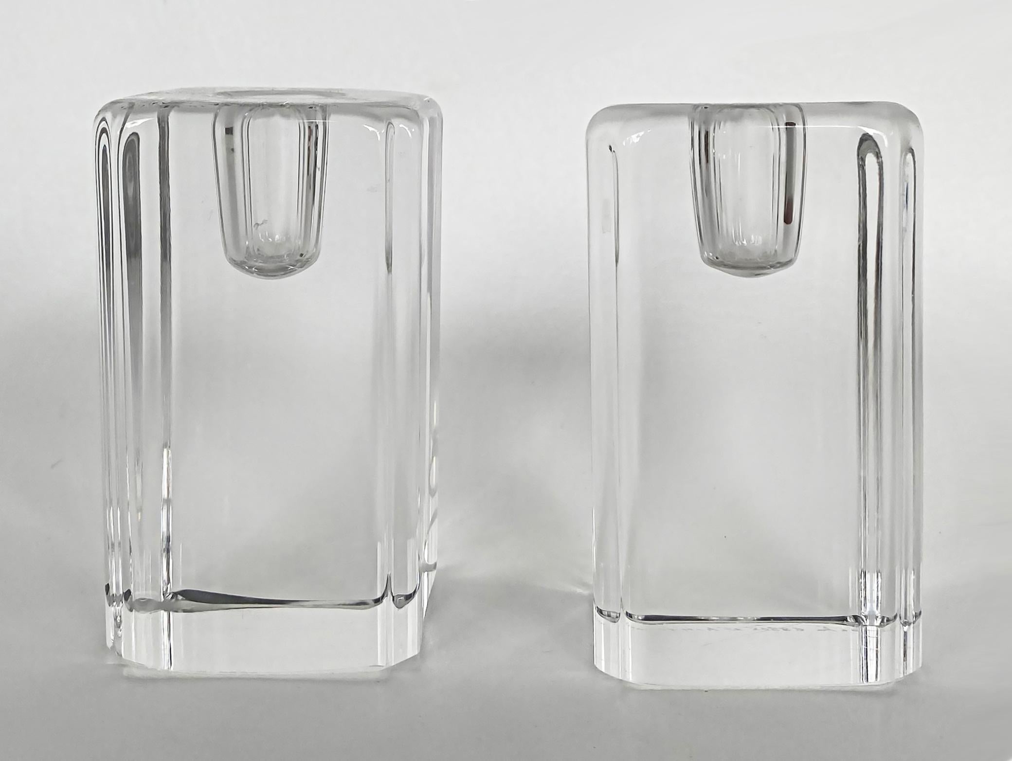 Kosta Boda Anna Ehrner short crystal candle holders, pair

Offered for sale are two short block-style candle holders in clear crystal, signed Kosta and Ehrner underneath on the bases. Each base is hand-signed with Kosta, the model number, and