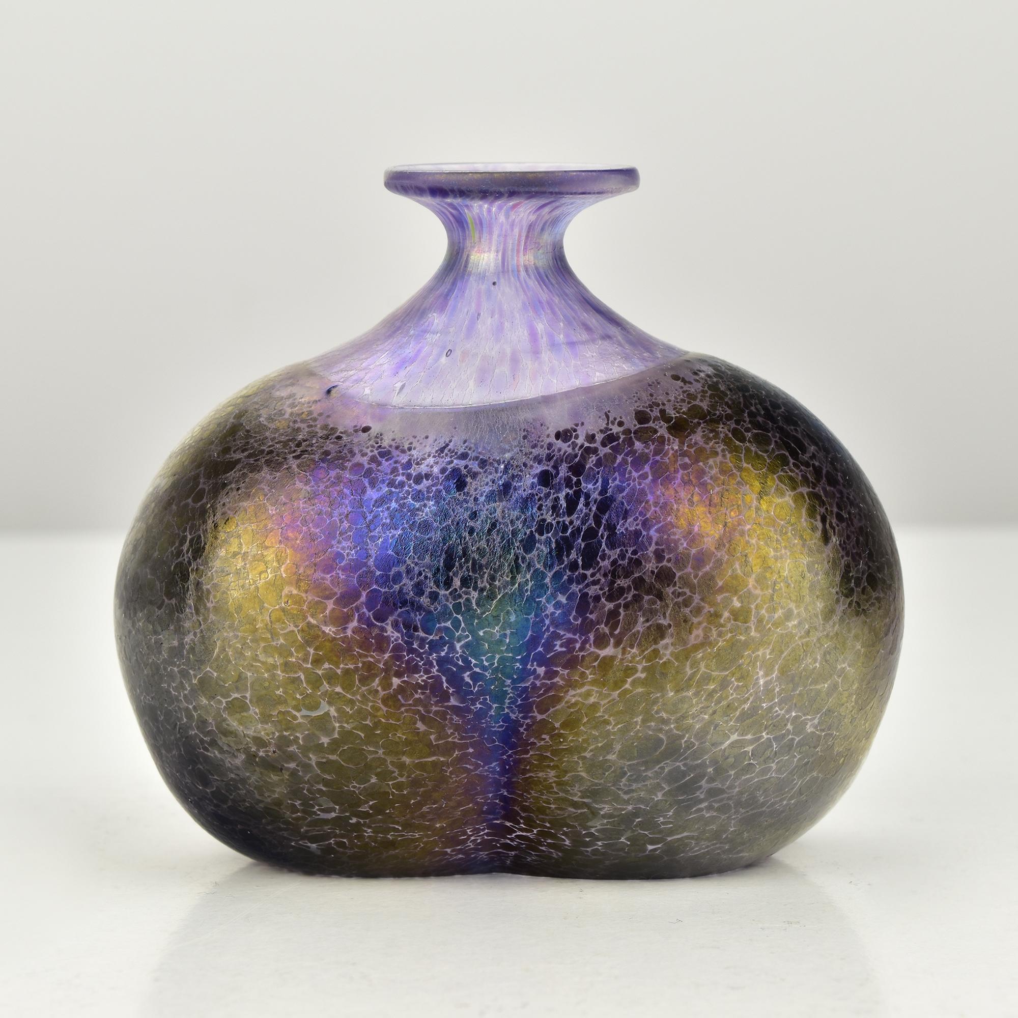 This exquisite mini object vase is a standout piece from Bertil Vallien's iconic Volcano series, designed in 1981. The unique double bubble shape is enhanced by the stunning iridescent, oily décor that shimmers with hues of purple, gold, and black.