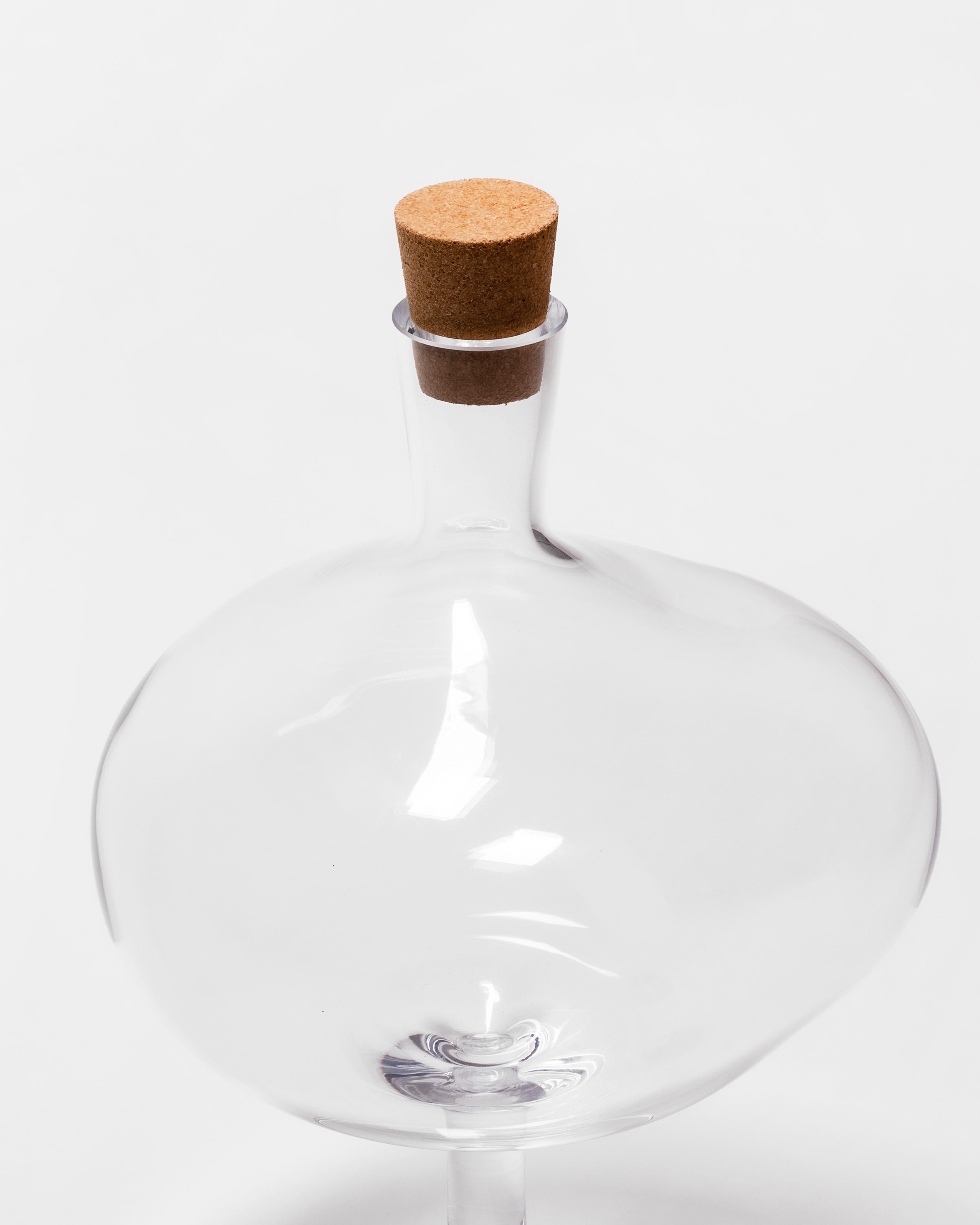 Like a tall wineglass, Bod balances confidently while its bowl captures the play of light. With their sheer and tall shape, the bottles are a piece of art that stands grounded in every home. The clear glass bottle on a foot can be used as a