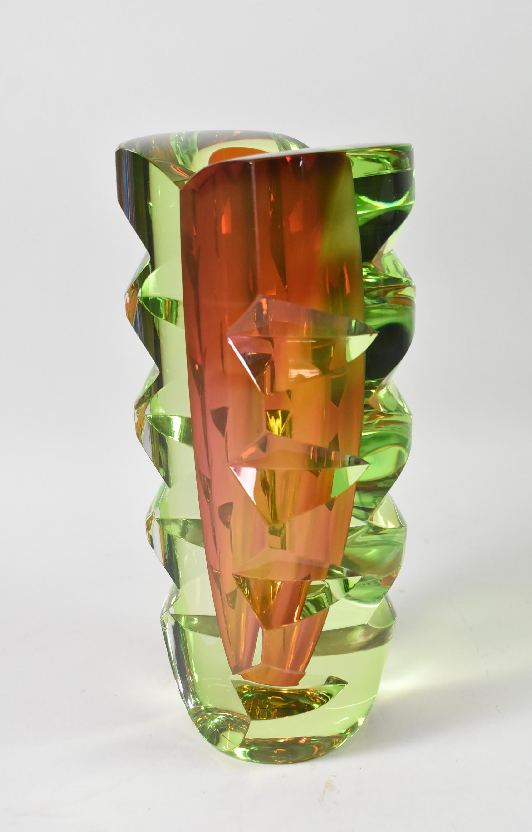 Questo vaso del XX secolo è stato disegnato da Goran Warff per Kosta Boda. Il vaso ha una forma affusolata e un esterno verde con ritagli di prisma. L'interno del vaso è Sommerso in mirtillo rosso. La parte inferiore del pezzo è firmata 