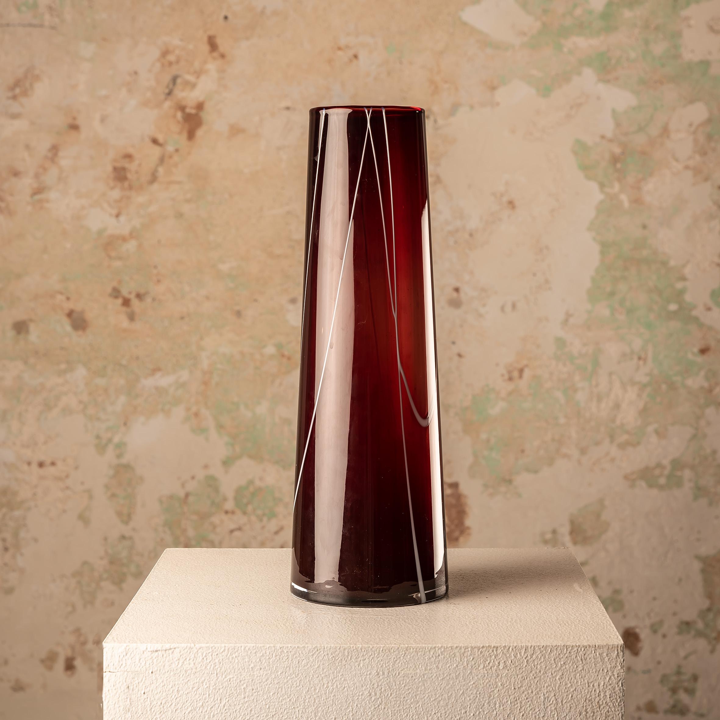 This Kosta Boda Granate glass vase designed by Anna Ehrner is a compelling piece that seamlessly blends artistry with functional design. Ehrner, known for her innovative approach to glasswork, has created a vase that exudes contemporary elegance and