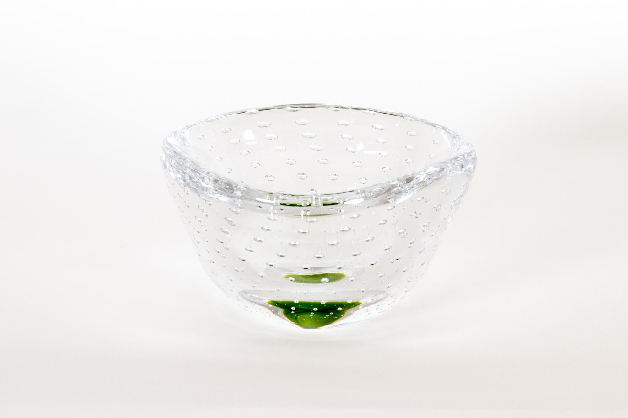 Bol en verre Kosta de Vicke Lindstrand 1950s
Petit bol en verre soufflé à la main, en verre transparent avec un soupçon de vert. Avec des bulles d'air décoratives en forme de spirale. Légèrement triangulaire. 
Signé en bas : Kosta LH 1307.
Très