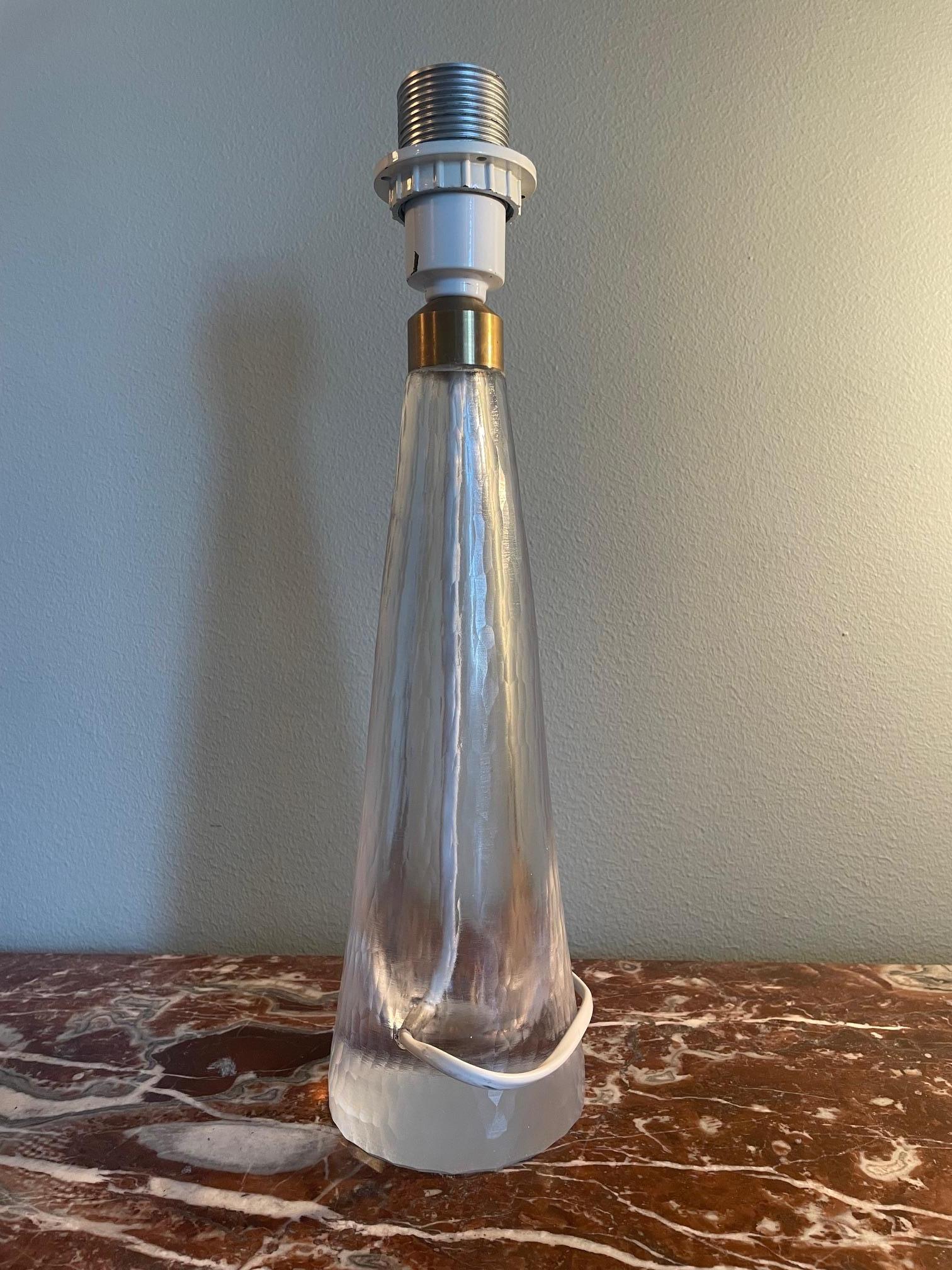Questa squisita lampada da tavolo, disegnata da Vicke Lindstrand per Kosta negli anni '50, esemplifica l'eleganza del design The Moderninavian. La lampada è dotata di una base in vetro cristallo smerigliato che mette in mostra la firma artistica di