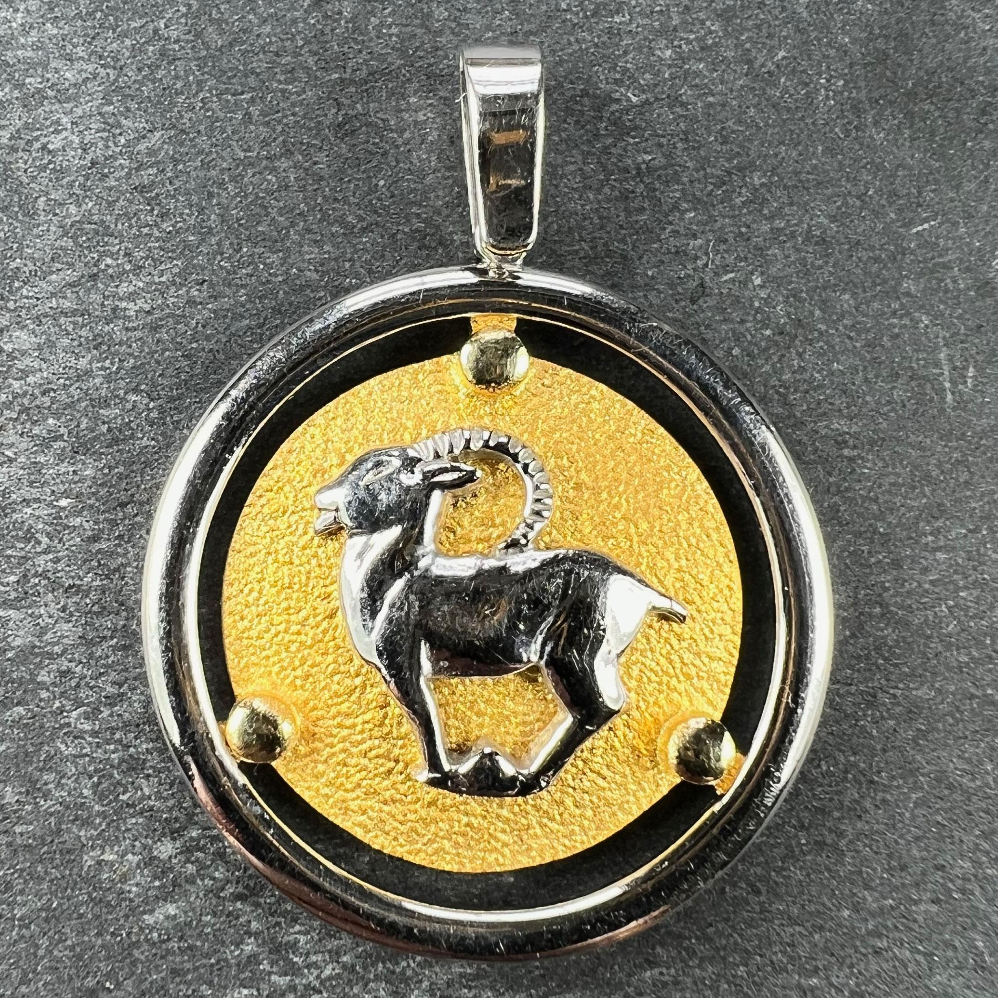 Pendentif à breloques en or jaune 14 carats (14K) représentant le signe zodiacal du Capricorne sous la forme d'une chèvre en or blanc sur un disque texturé en or jaune maintenu dans une monture circulaire en or blanc. Signé Kosun et marqué 585 pour