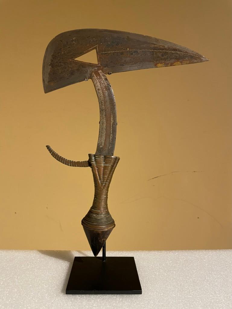 A Kota style 'Bird-head' ceremonial throwing knife, of classic form, with pierced triangular 'eye', the grip and spur bound with brass.  Intricate geometric incised decoration to various parts of the shaft and blade, the blade emerging from a