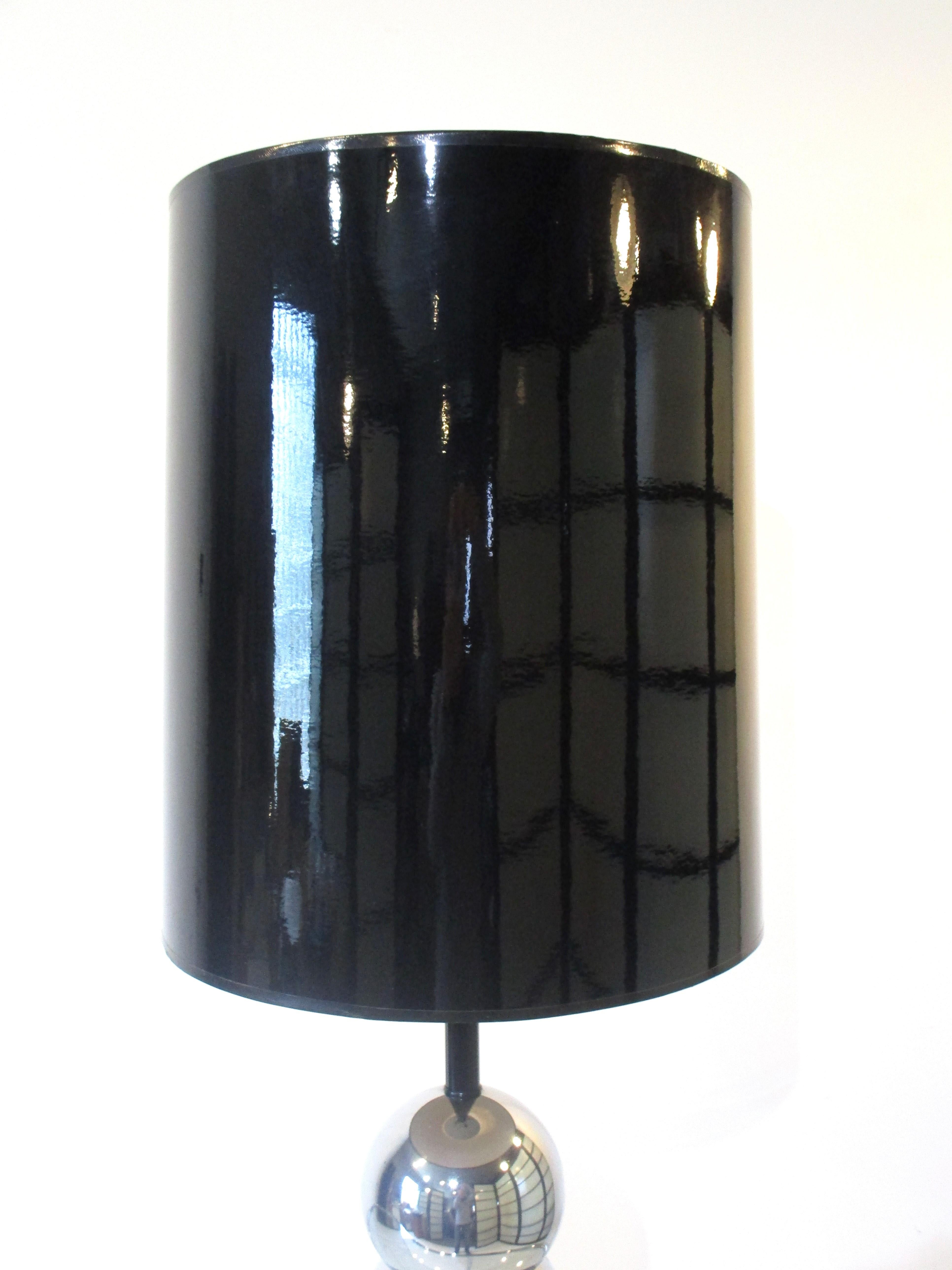 A stacked ball caterpillar styled chrome table lamp with a high gloss black barrel shade. Sitting on a satin black base and having a black matching socket shaft designed and manufactured by the Kovacs Lighting company.