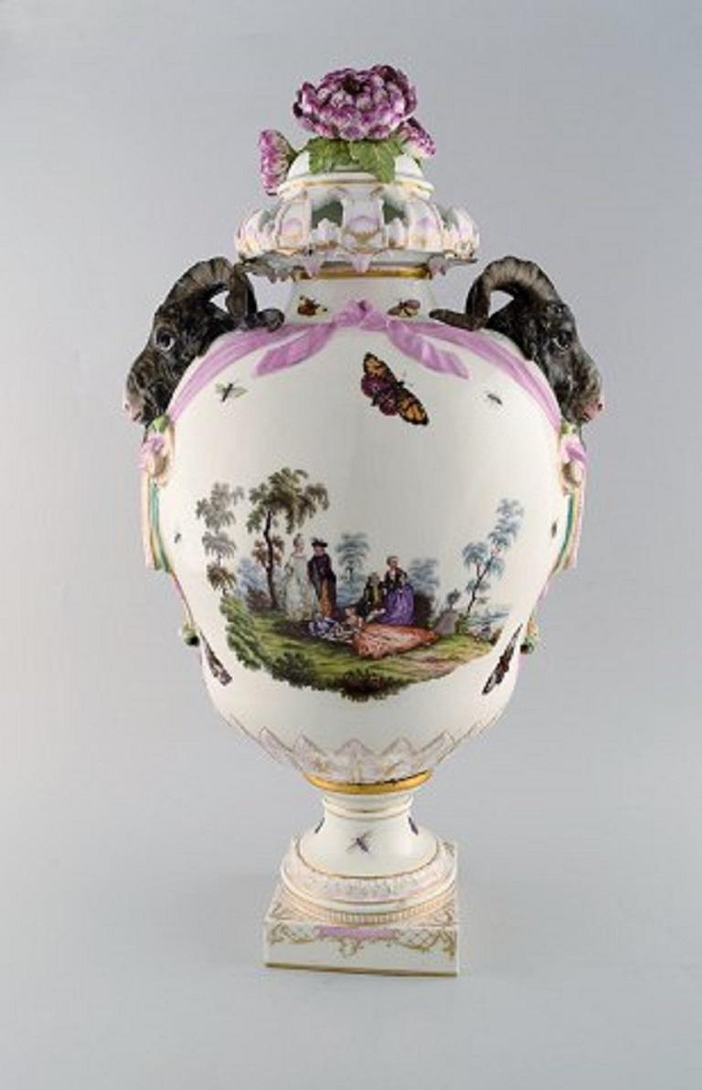 KPM, Berlin. Monumental antique lidded potpourri vase in porcelain. Overglaze.
Goats and pink flowers in relief and hand painted with butterflies, romantic scenery with Fête galante scenes.
Museum quality, 1780s.
Measures: 60 x 34