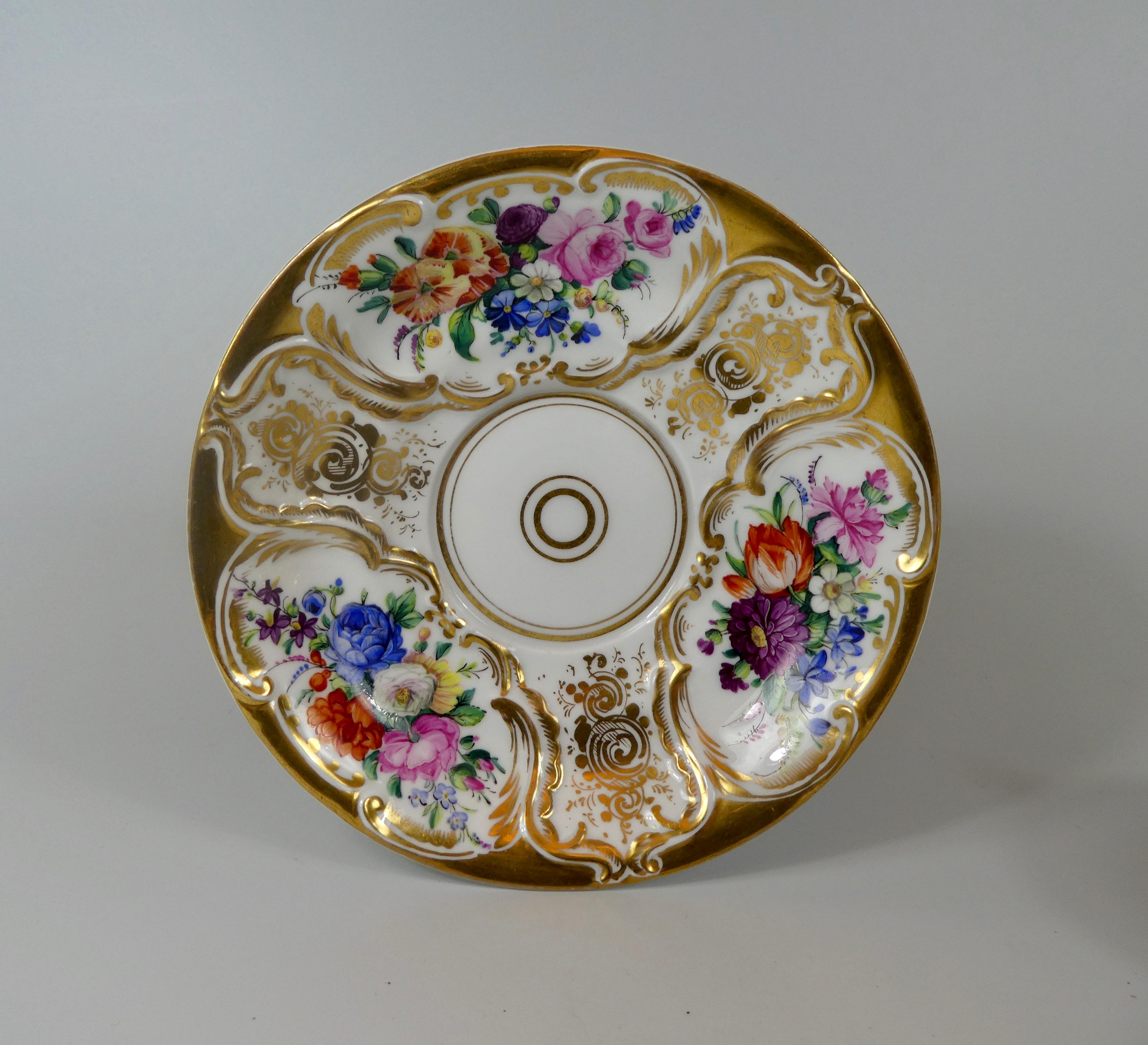 A fine KPM Berlin porcelain chocolate cup, cover and stand, circa 1860. The shaped and highly gilded cup, with moulded scroll panels containing hand painted sprays of flowers. Having an elaborate ‘C’ scroll handle. The stand and cover similarly